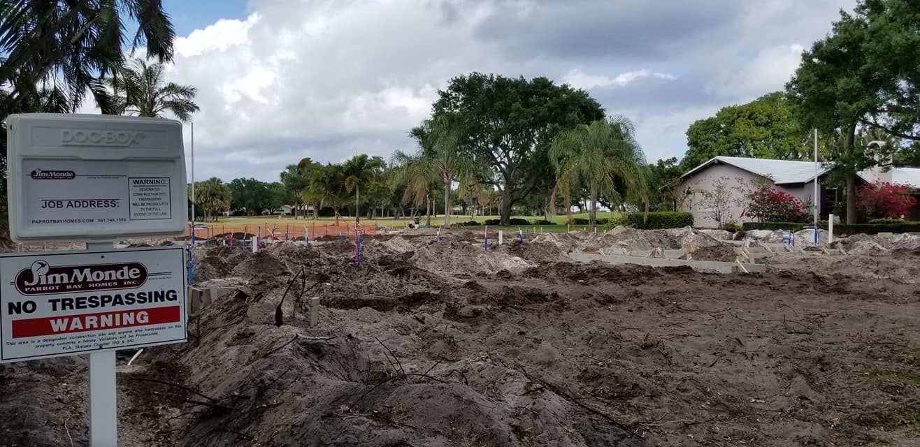 A sign that says no trespassing is in front of a dirt field.