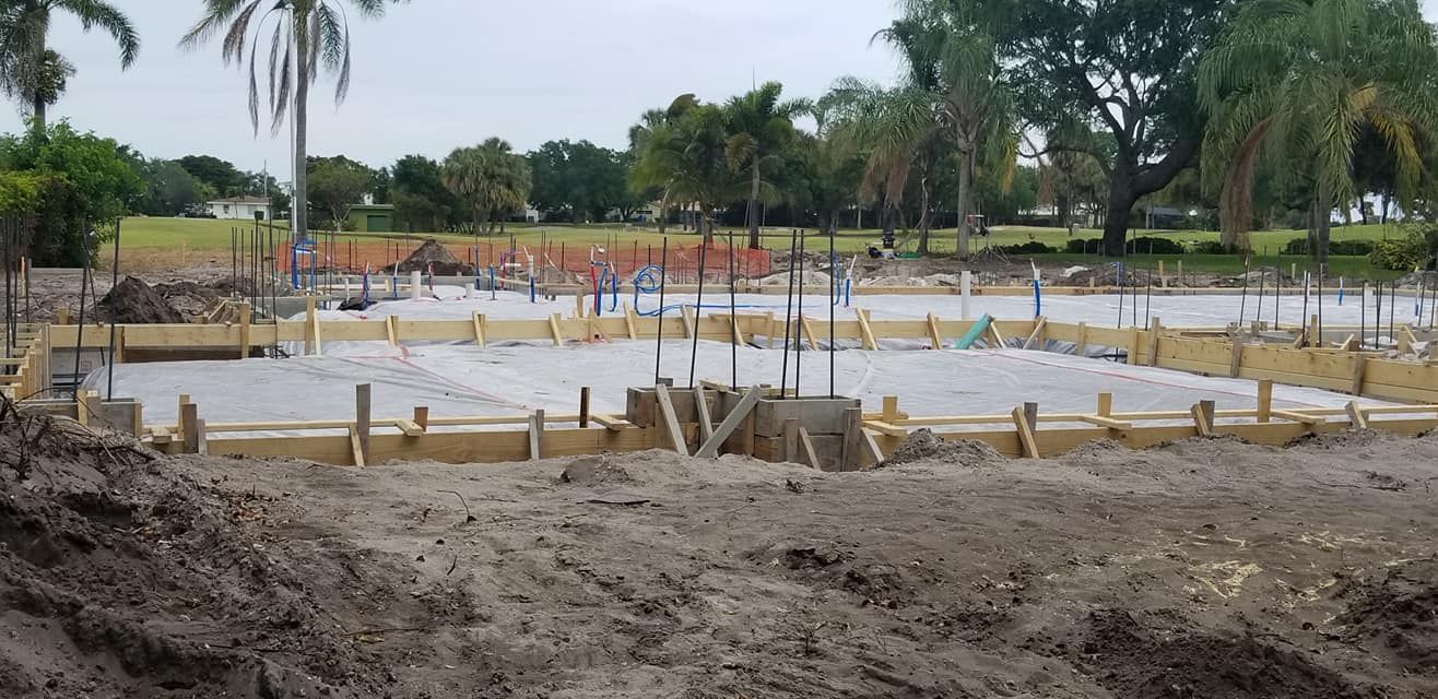 A construction site with a lot of dirt and trees in the background.