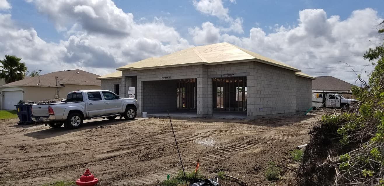 A white truck is parked in front of a house under construction.