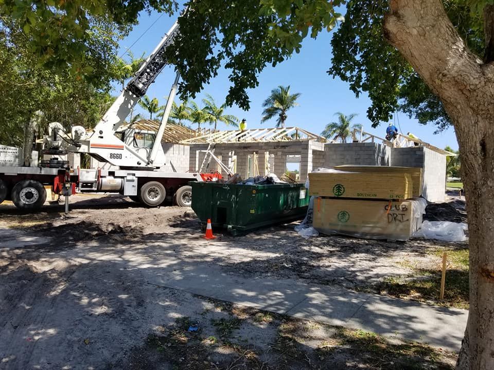 A truck with a crane on it is parked in front of a house under construction.
