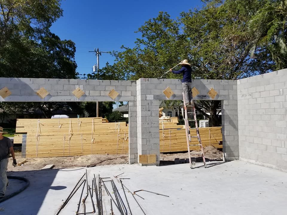 A man is standing on a ladder in front of a building under construction.