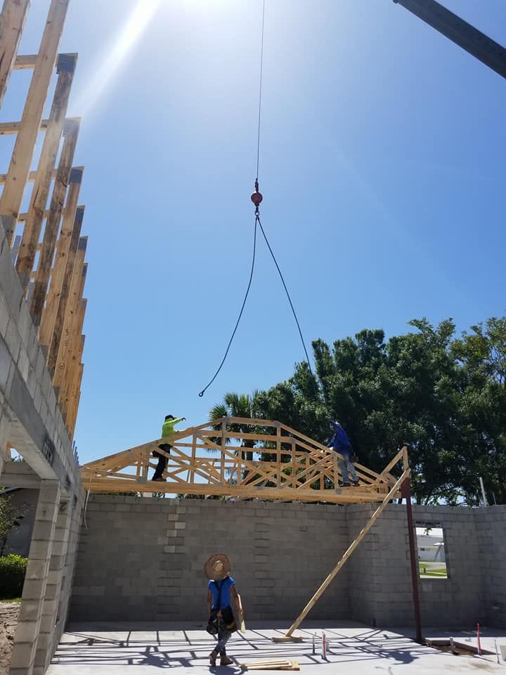A crane is lifting a wooden structure on top of a building under construction.