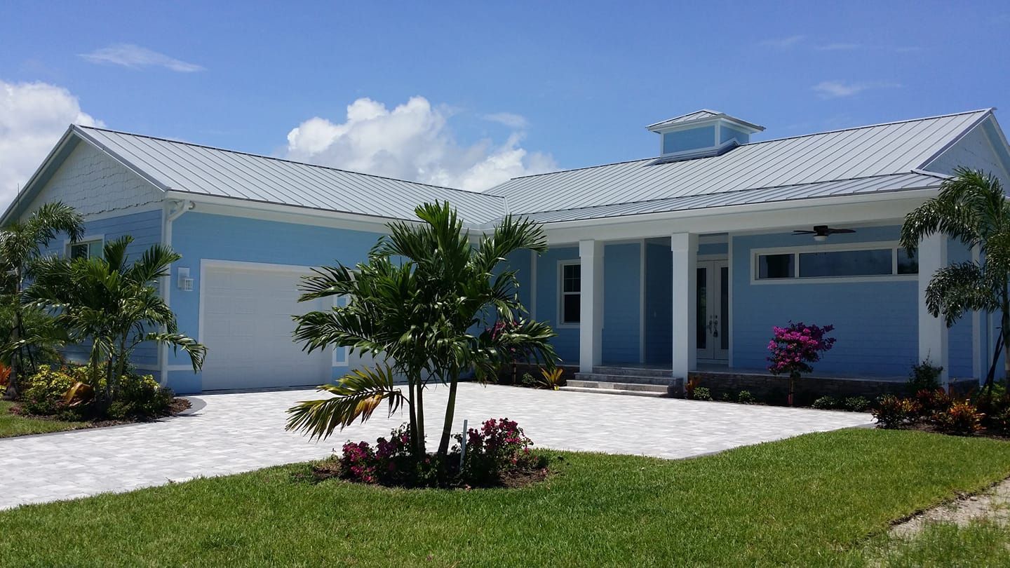 A blue house with a white roof and a driveway.