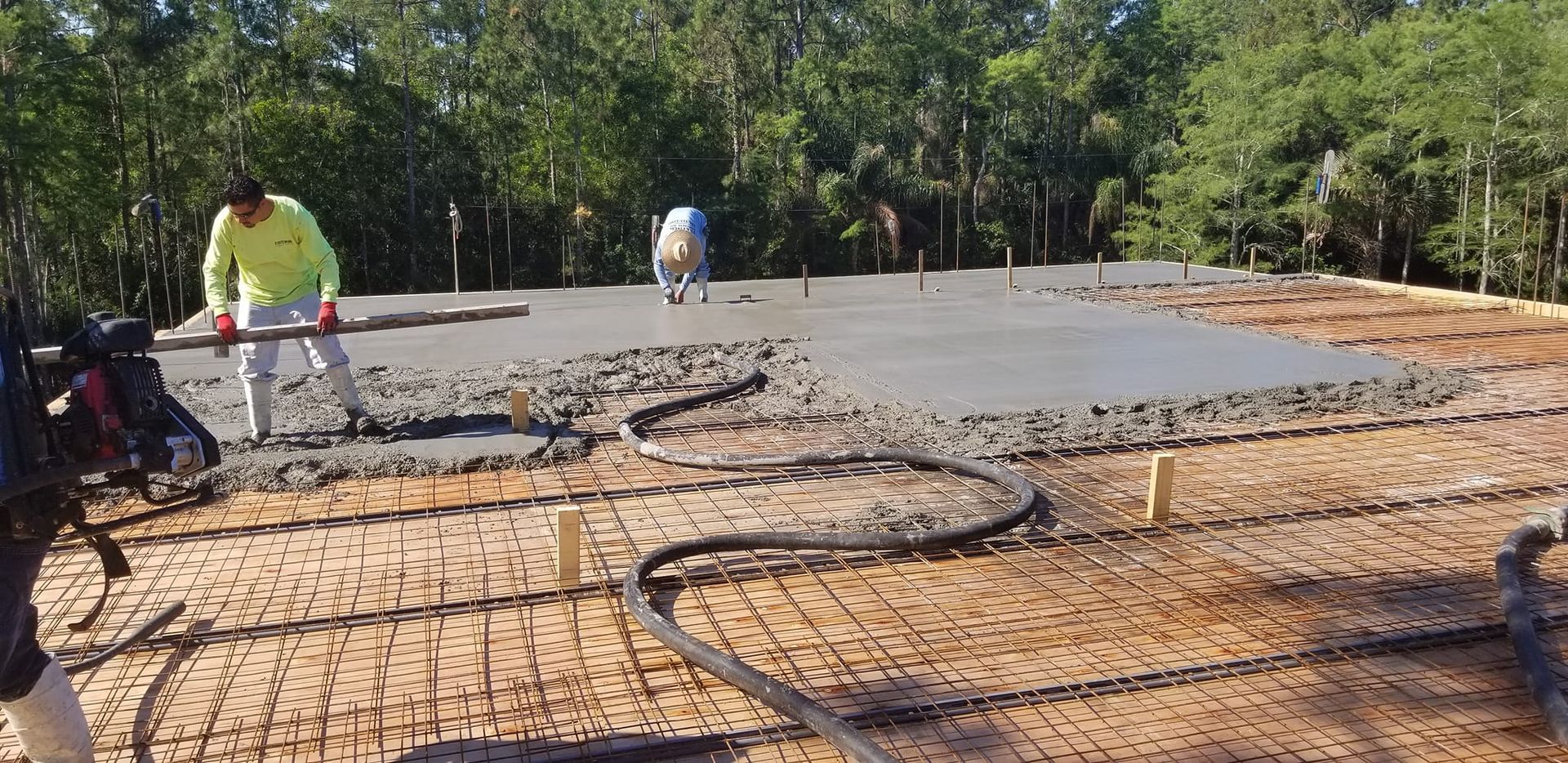 A group of construction workers are working on a concrete floor.