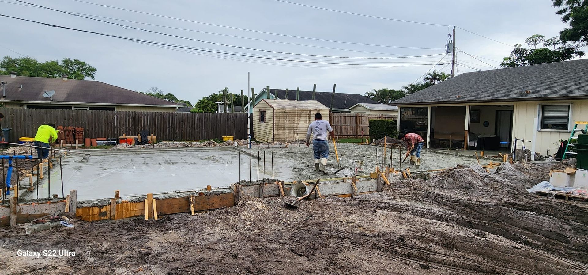 A construction site with a lot of dirt and a house in the background.