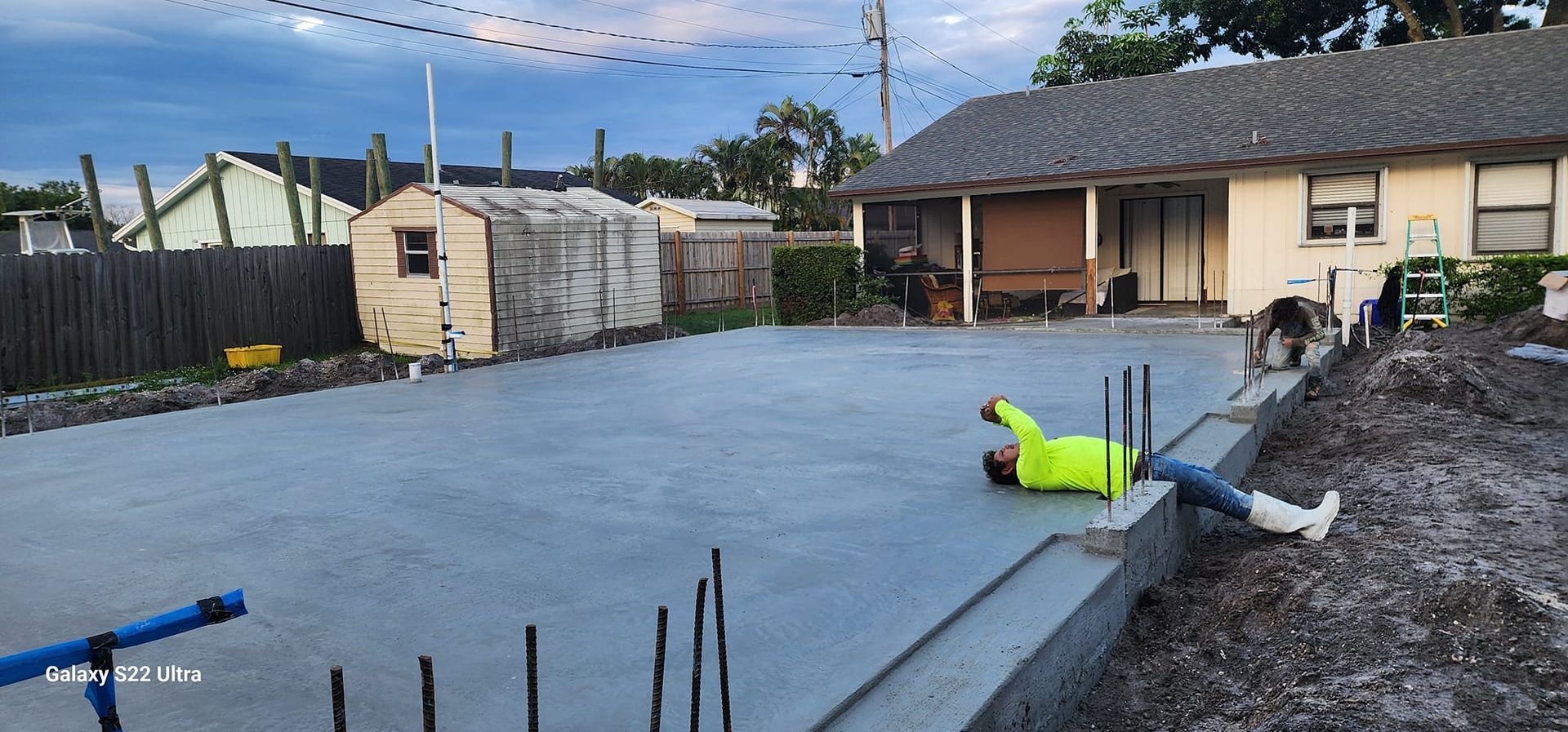 A man is laying on the ground in front of a house.