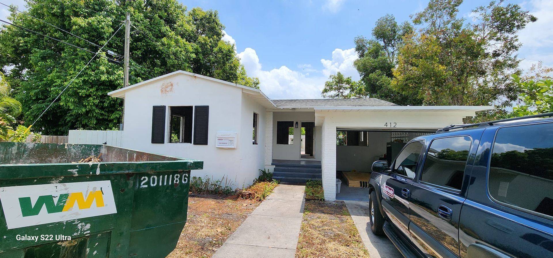A black truck is parked in front of a white house.
