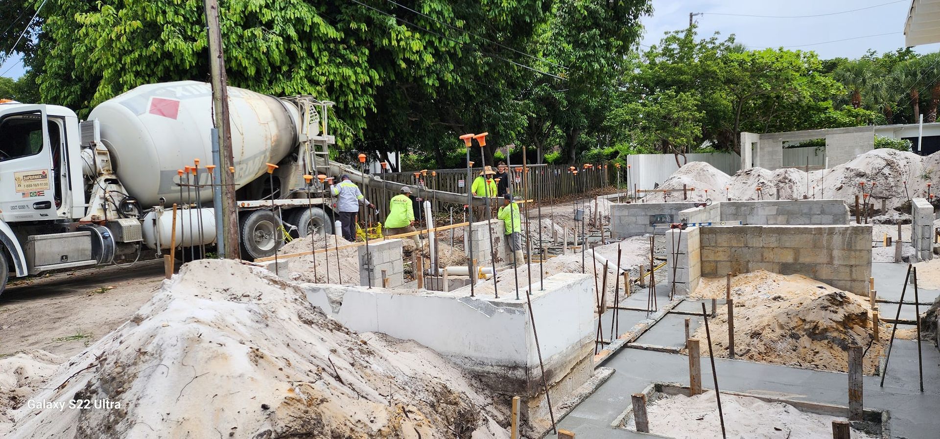 A concrete mixer truck is pouring concrete into a construction site.