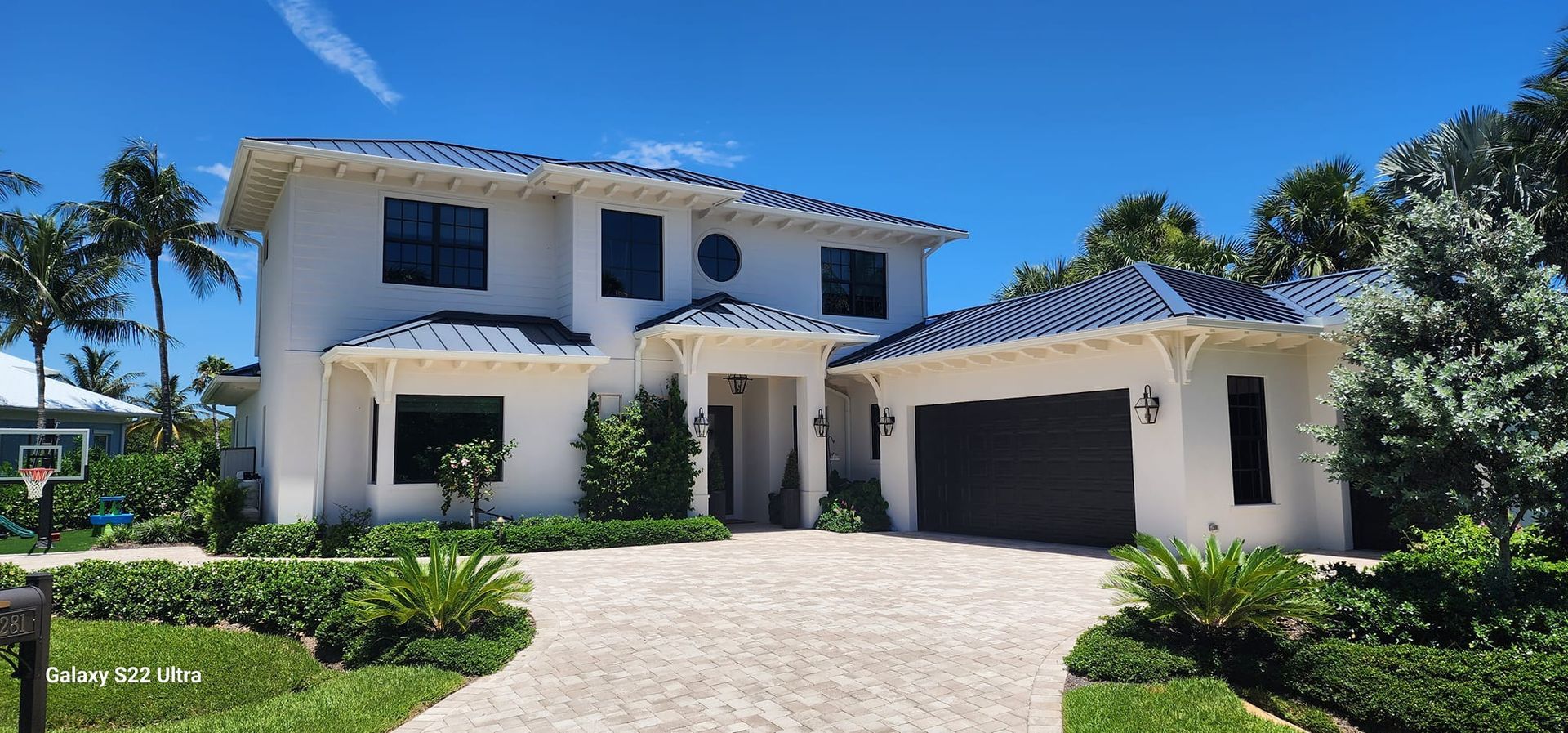 A large white house with a blue roof and a driveway