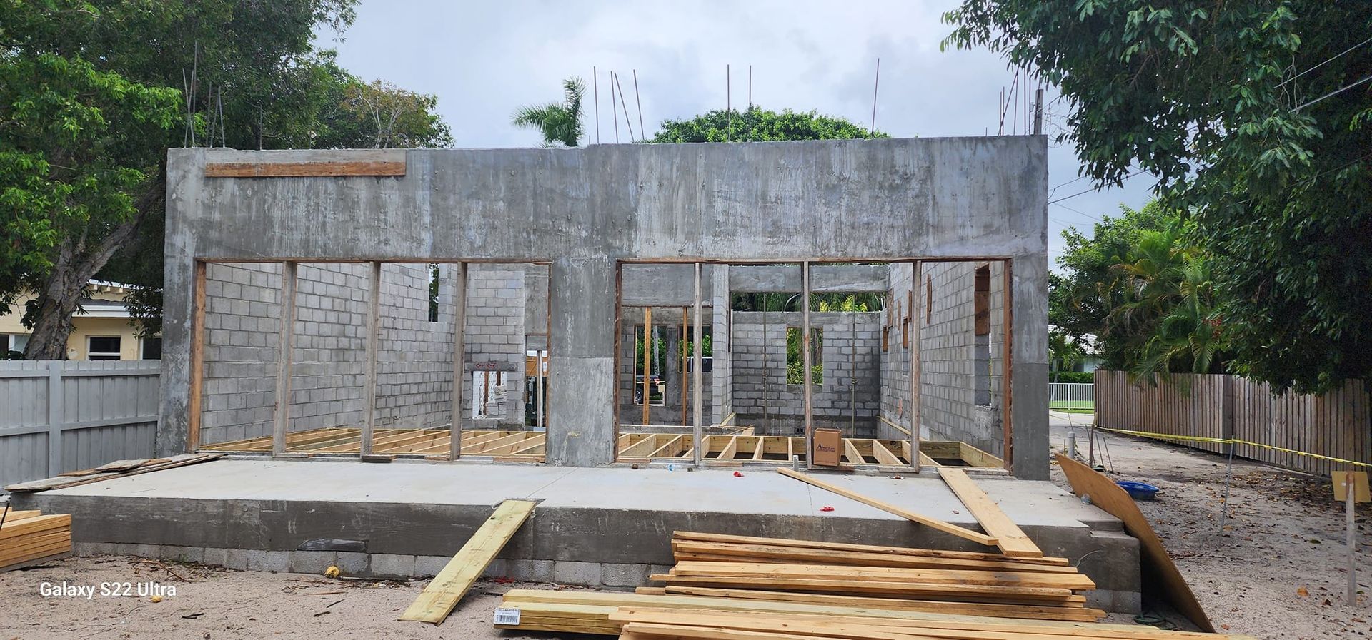 A building under construction with a lot of wood in front of it