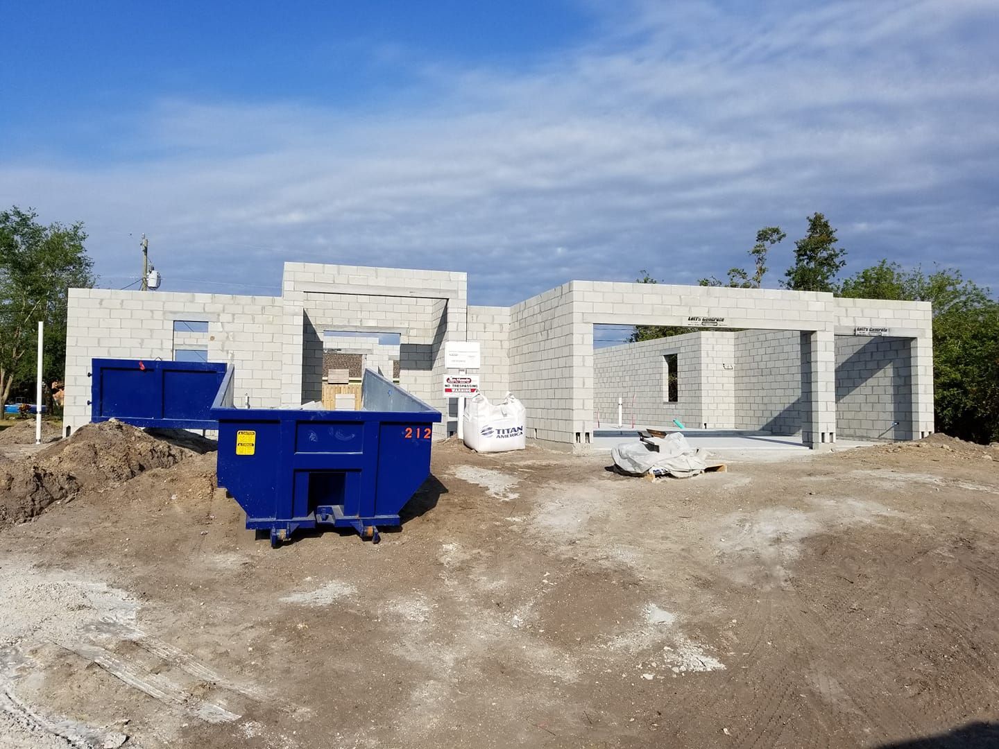A blue dumpster is sitting in front of a building under construction.