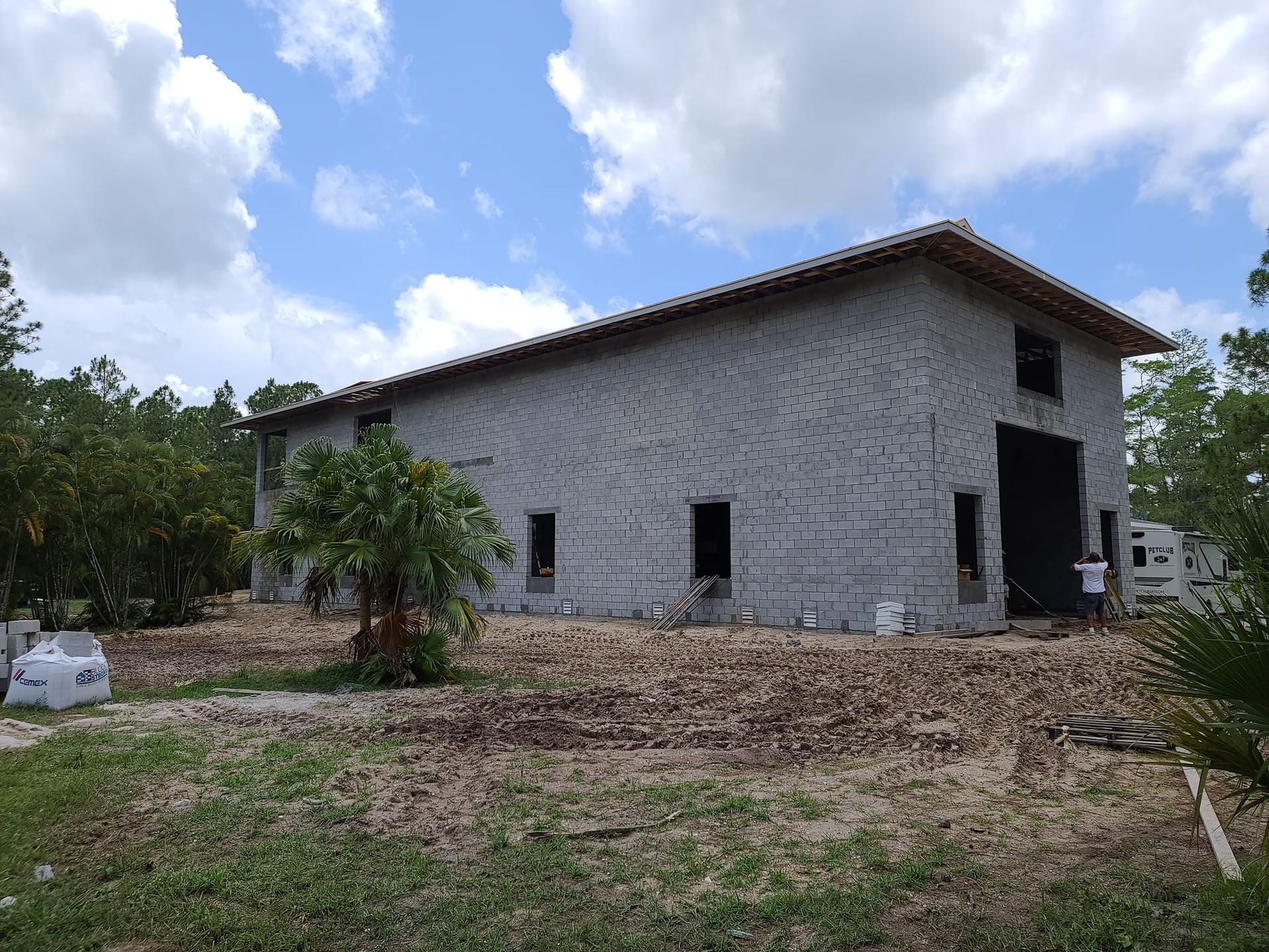 A large brick building is being built in the middle of a field.