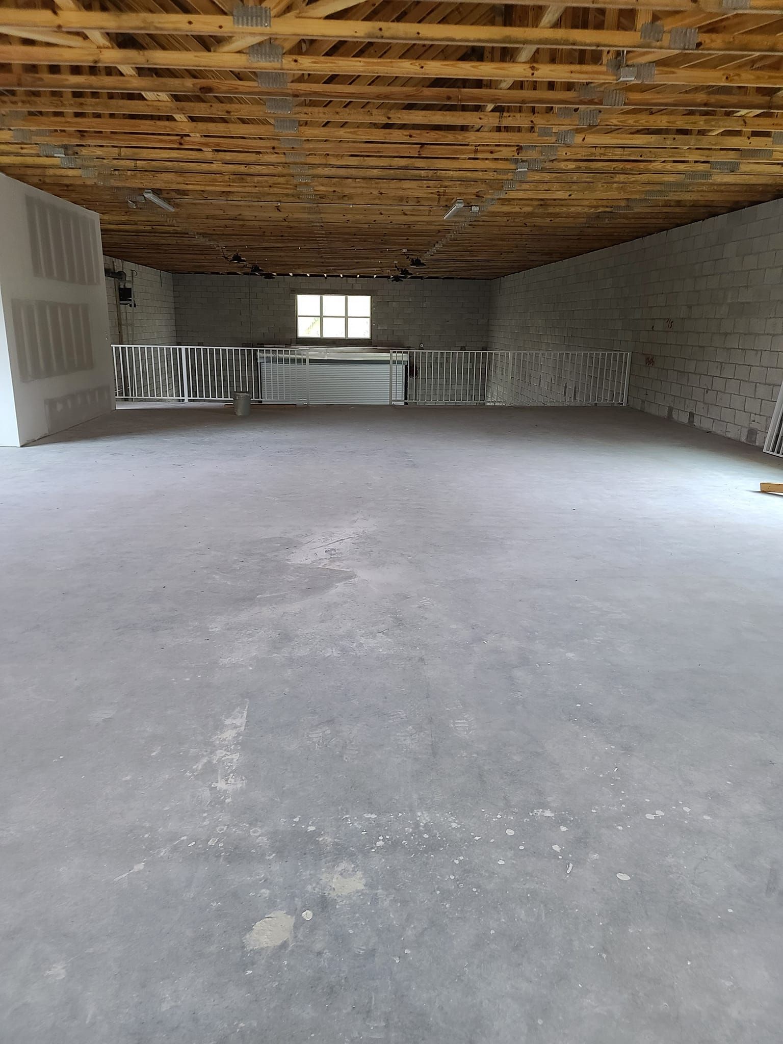 A large empty room with a wooden ceiling and a window.