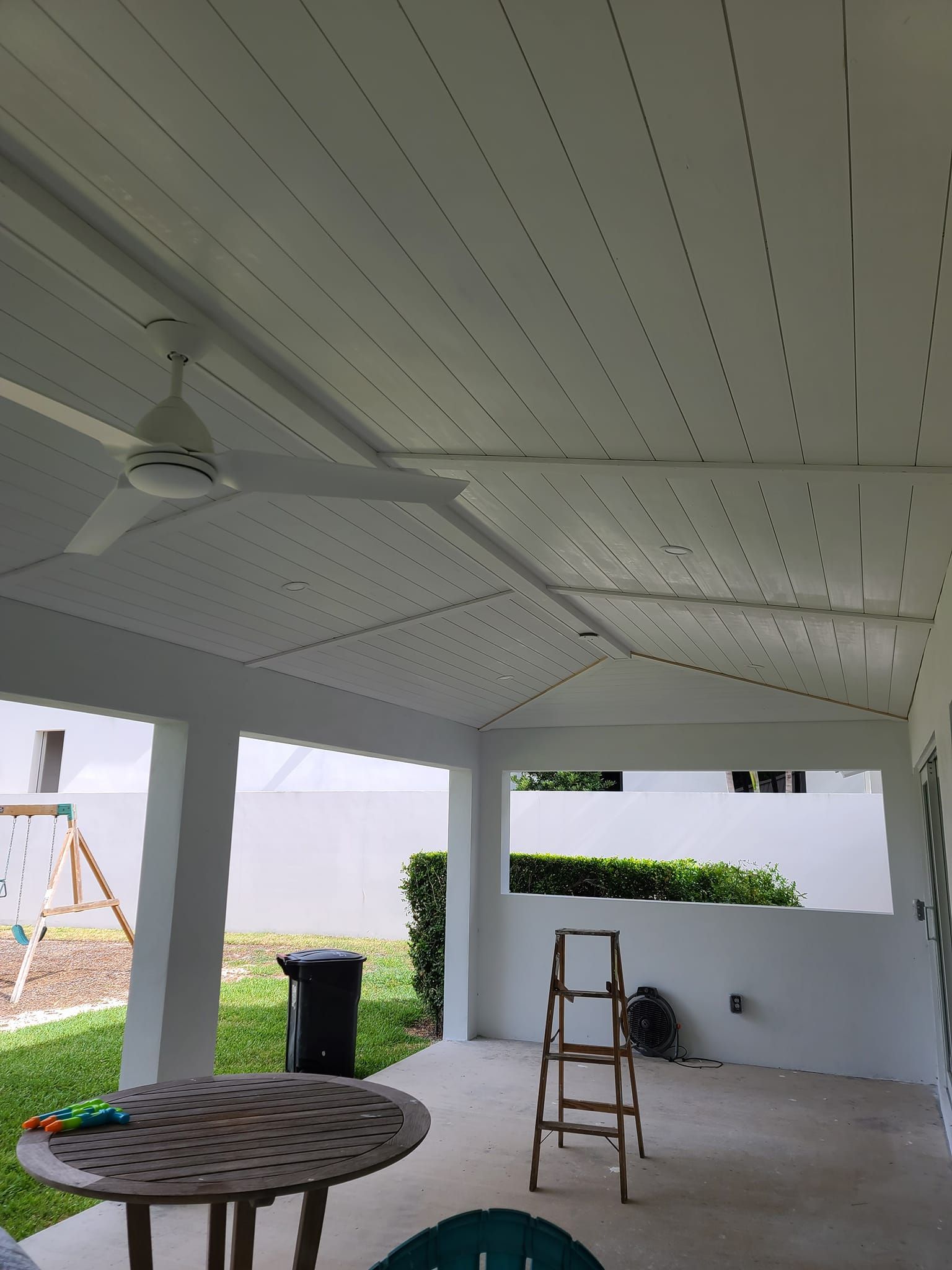 A ceiling fan is hanging from the ceiling of a porch