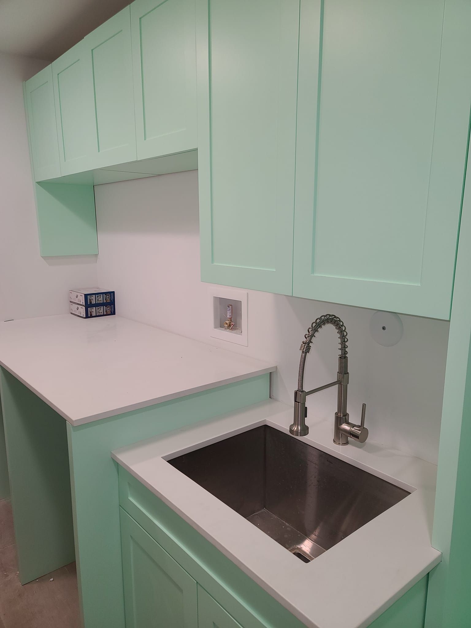 A kitchen with green cabinets and a stainless steel sink.