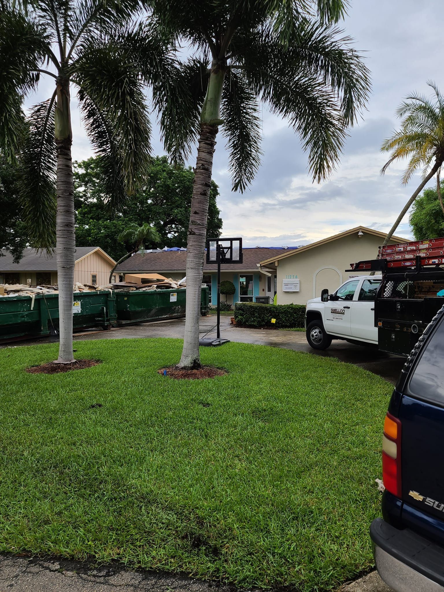 A truck is parked in front of a house with a basketball hoop in the backyard.