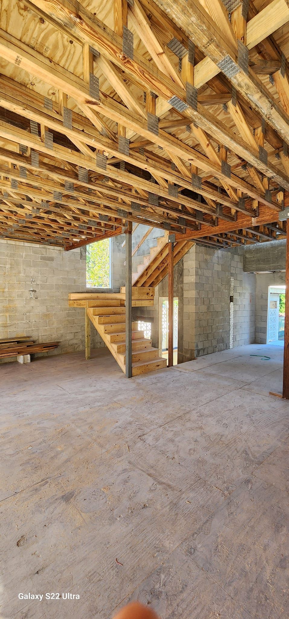 A large empty room with a wooden ceiling and stairs.