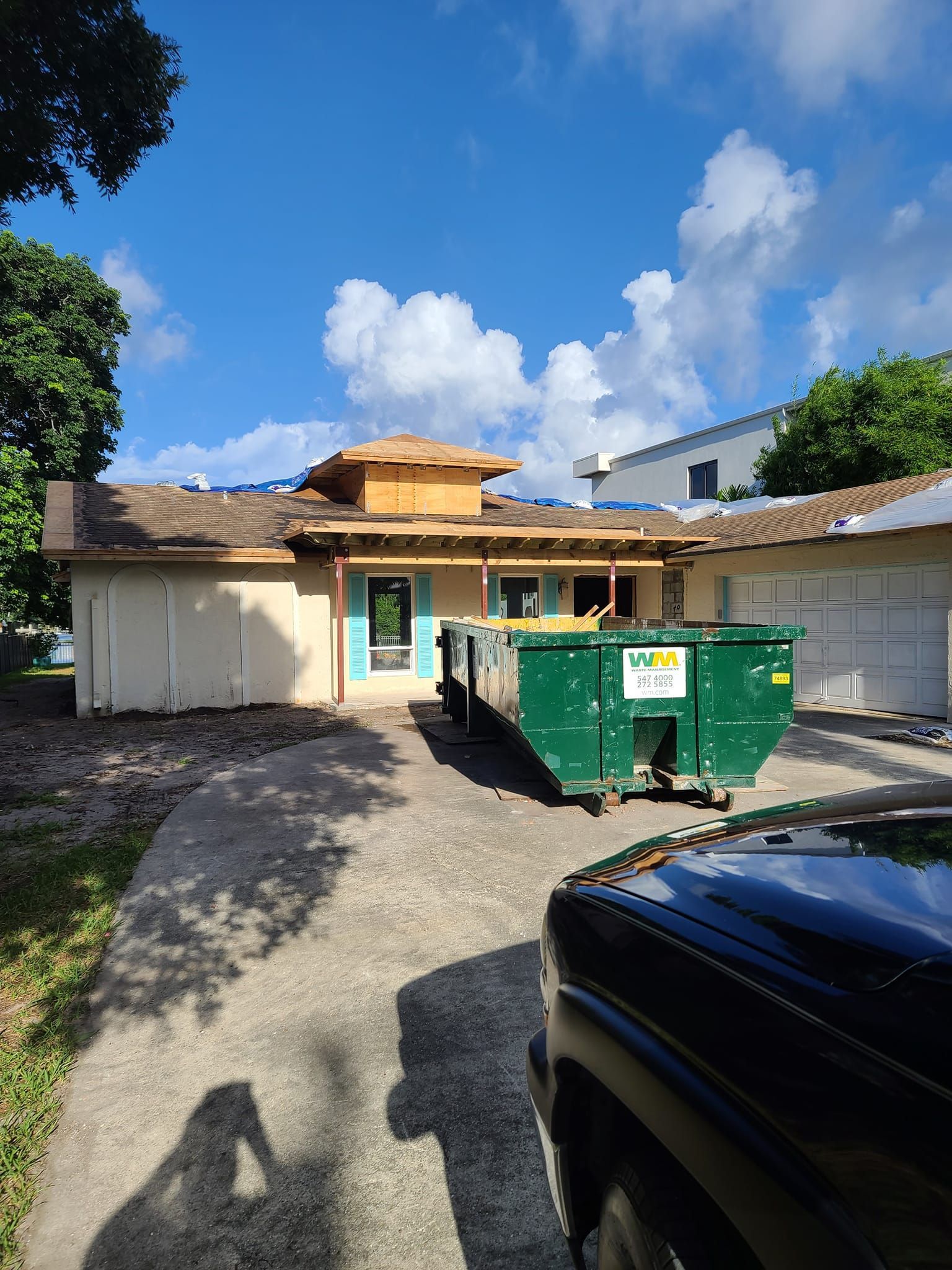 A dumpster is parked in front of a house under construction.