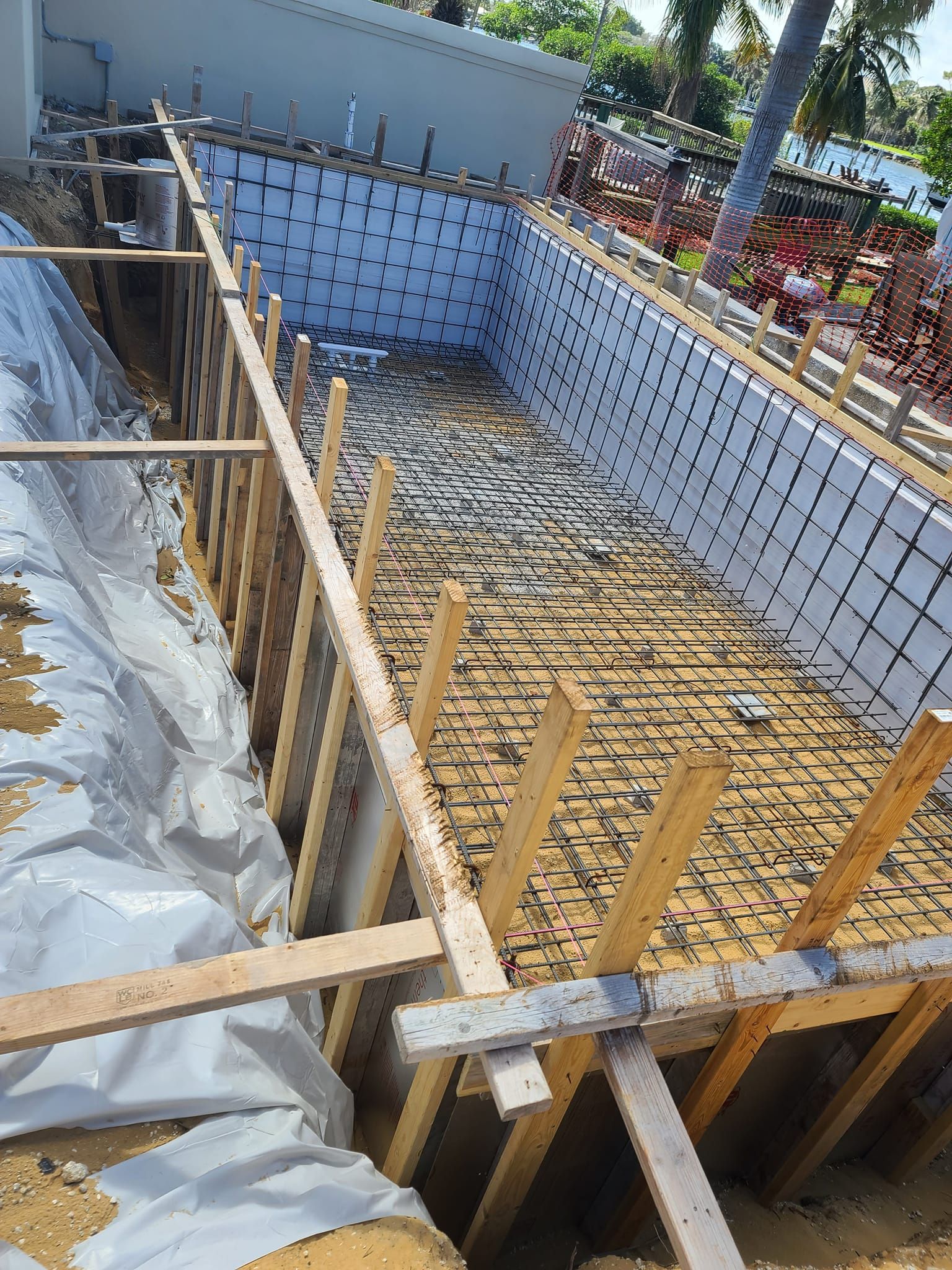 A swimming pool is being built in the backyard of a house.