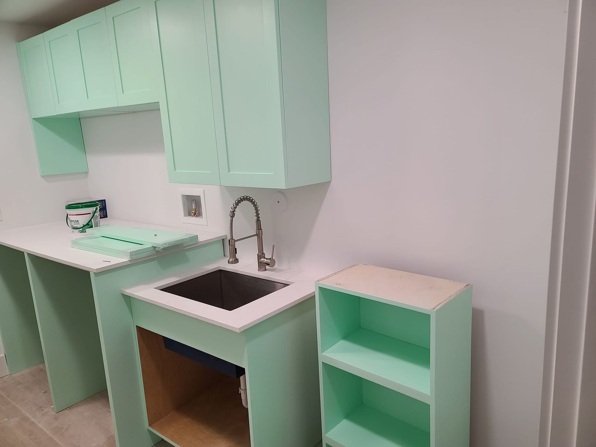 A kitchen with green cabinets and a sink.