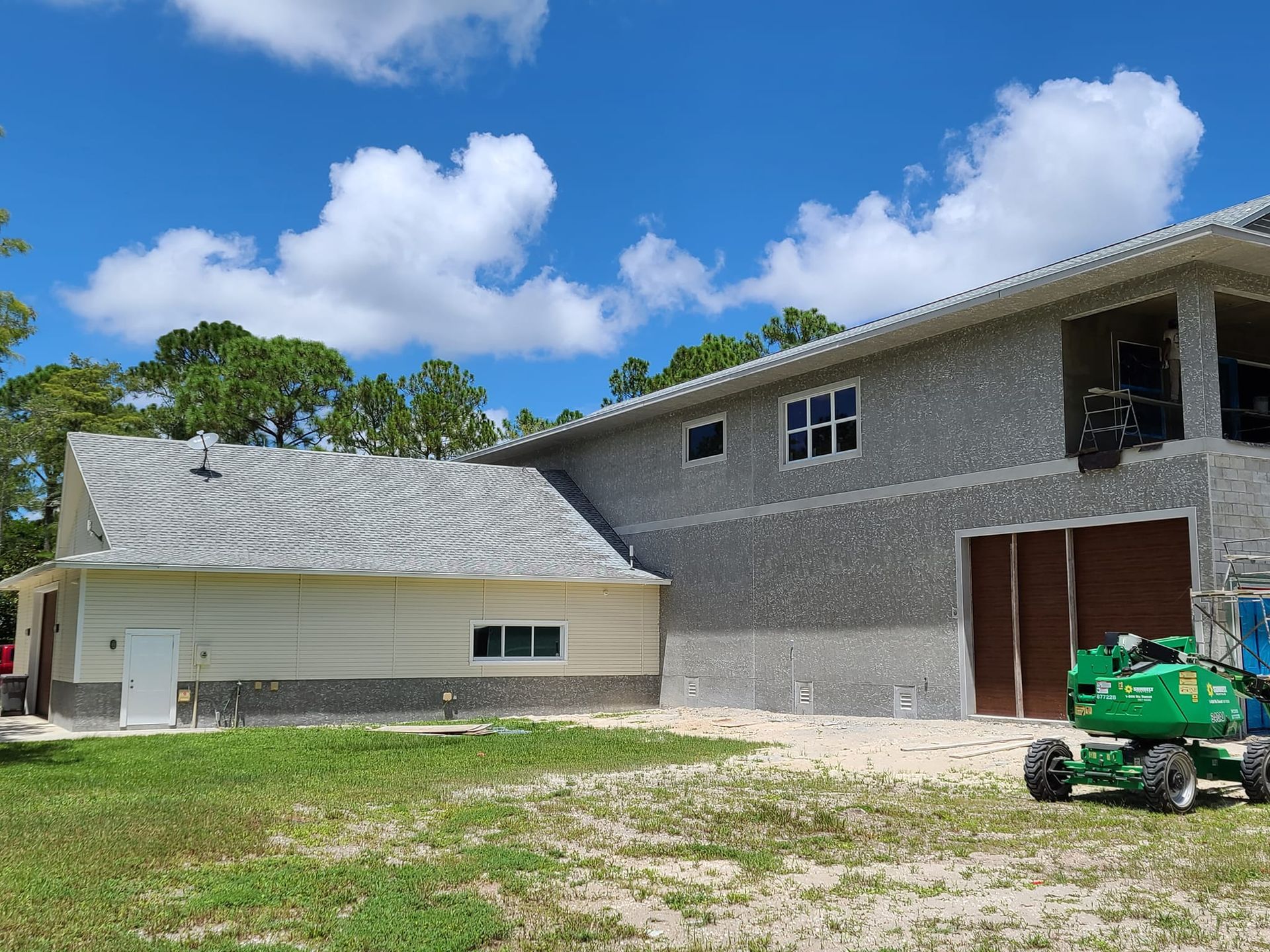 A green tractor is parked in front of a house under construction.