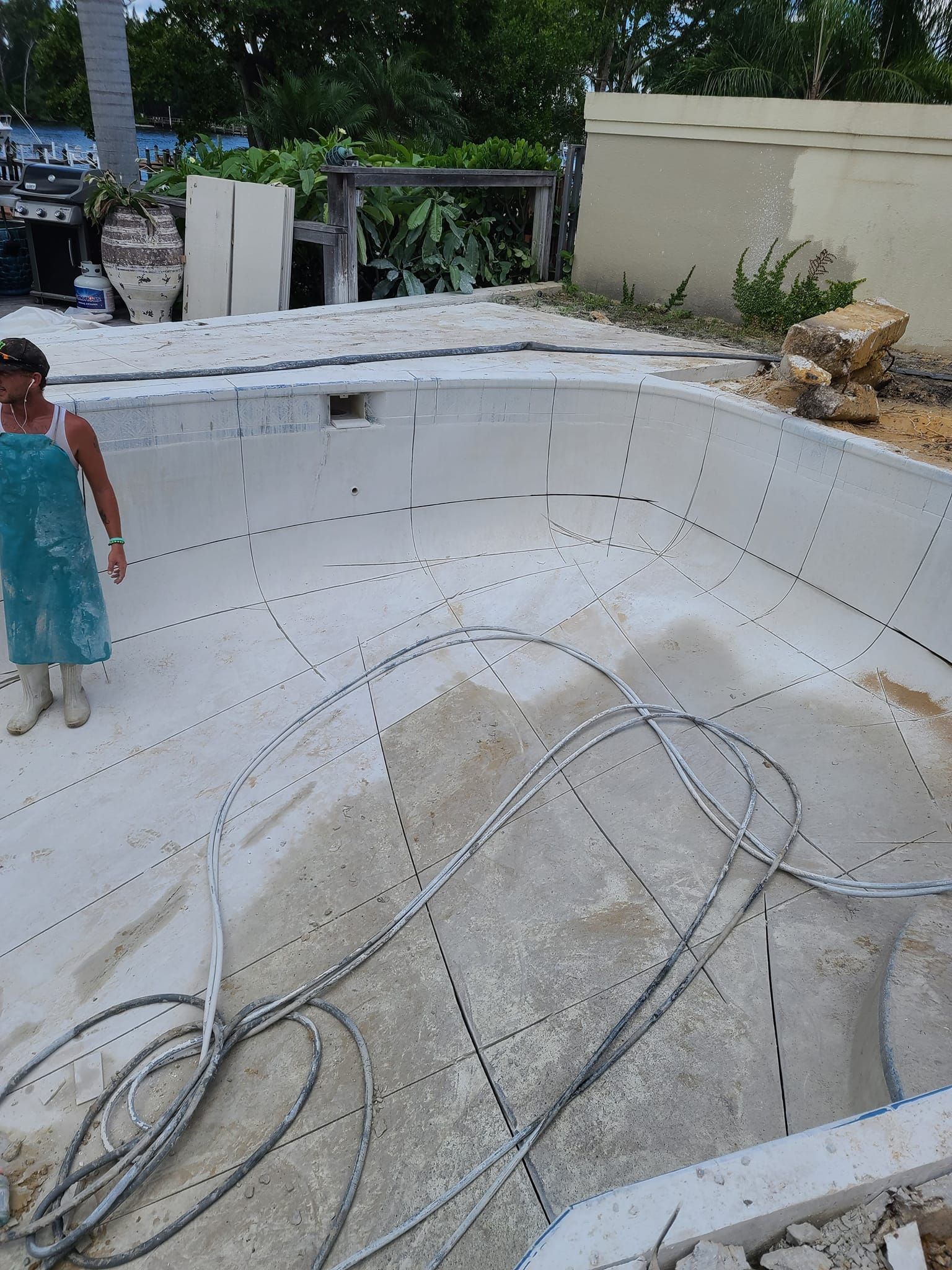 A woman in a blue dress is standing in front of a swimming pool under construction.