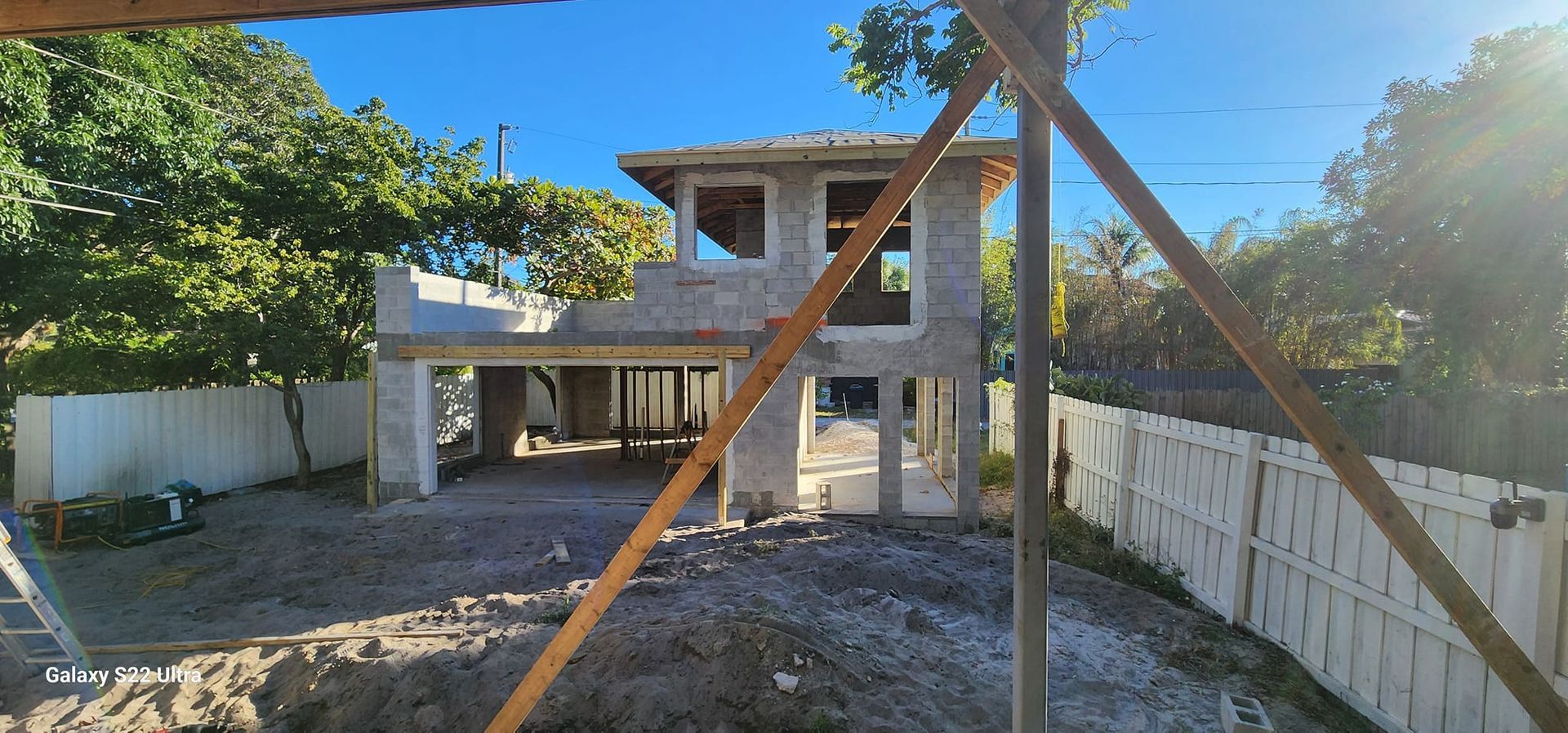 A house is being built next to a white fence.