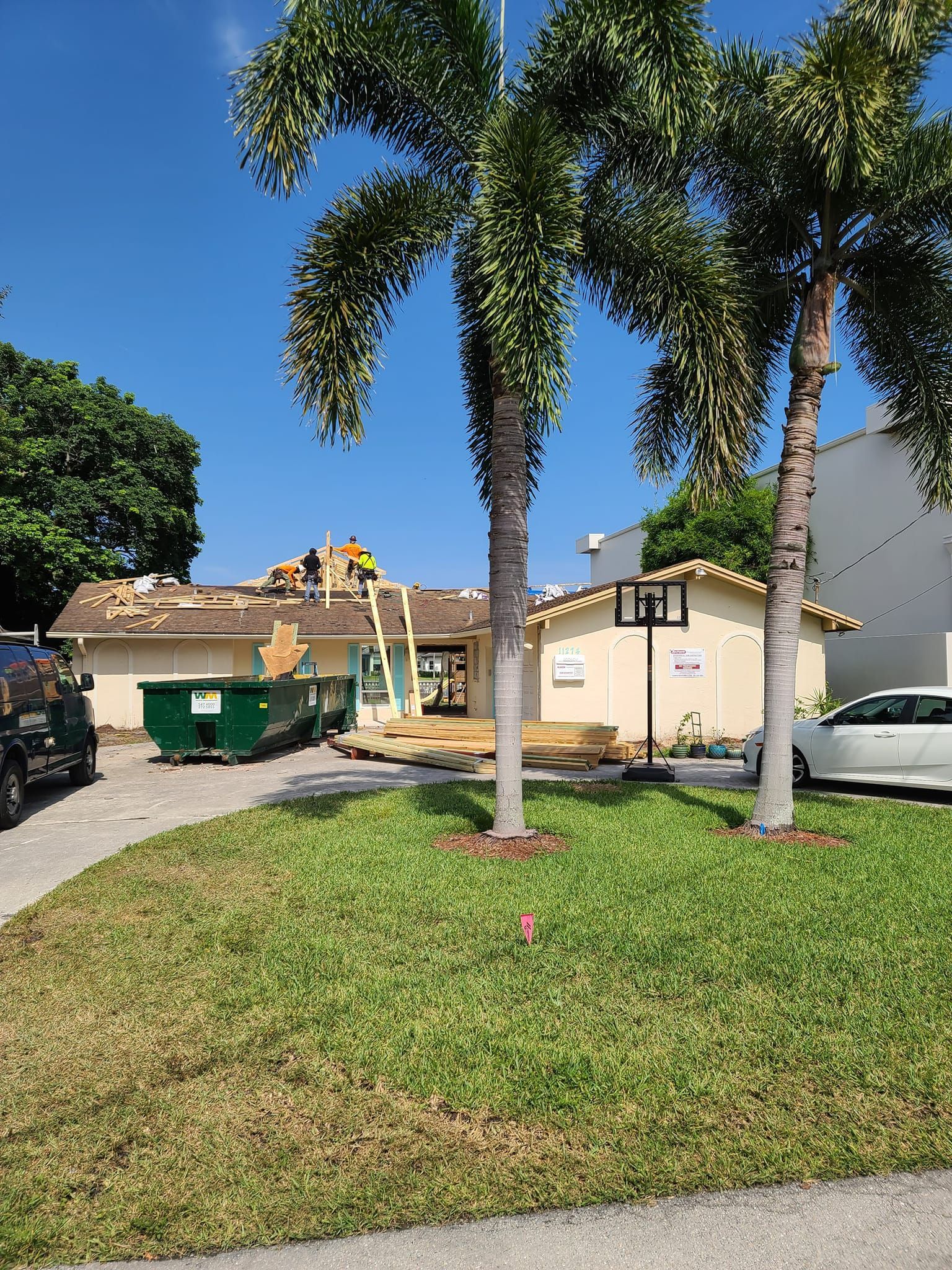 A house is being remodeled with a green dumpster in front of it.
