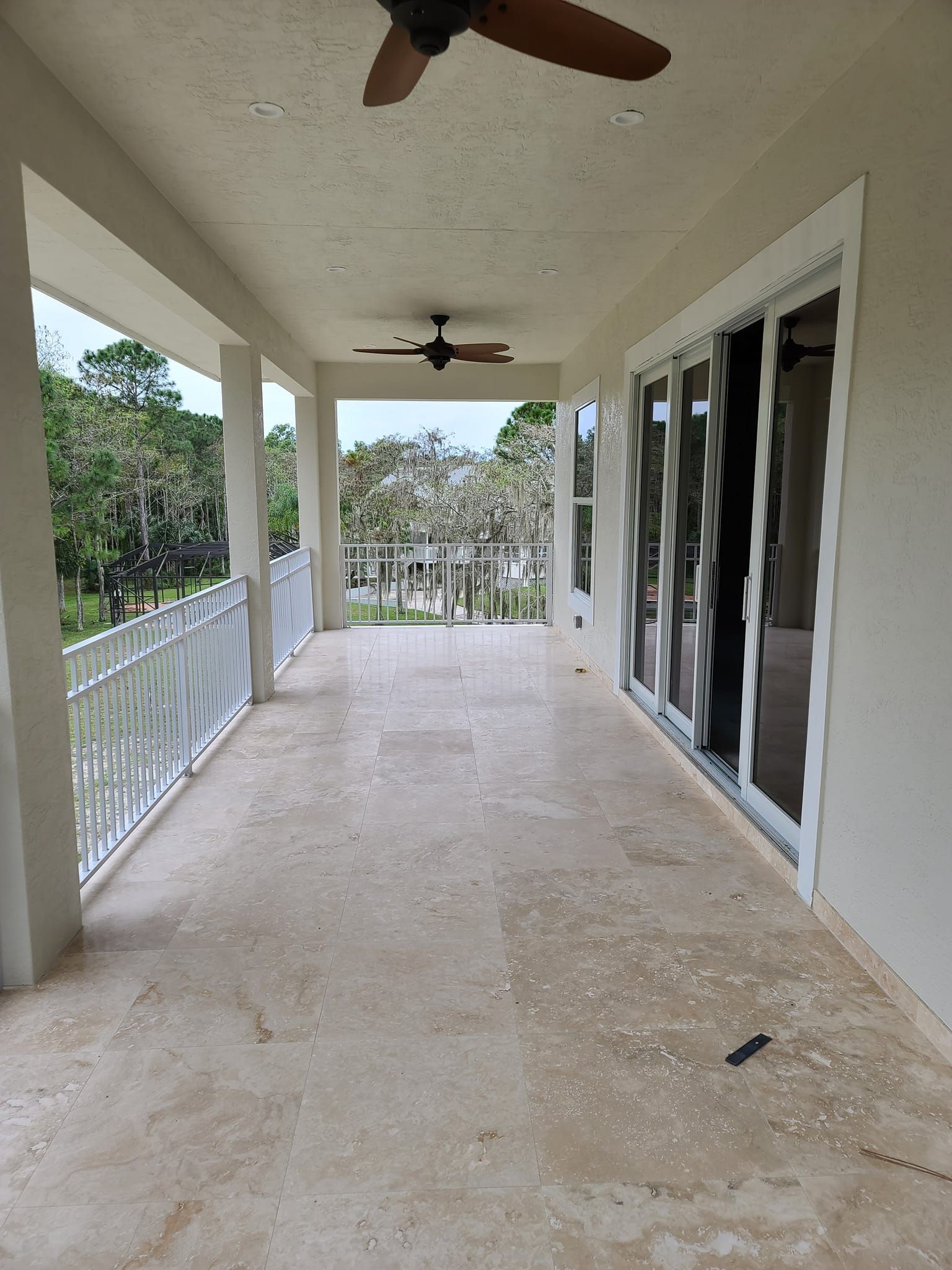 A large porch with a ceiling fan and sliding glass doors.