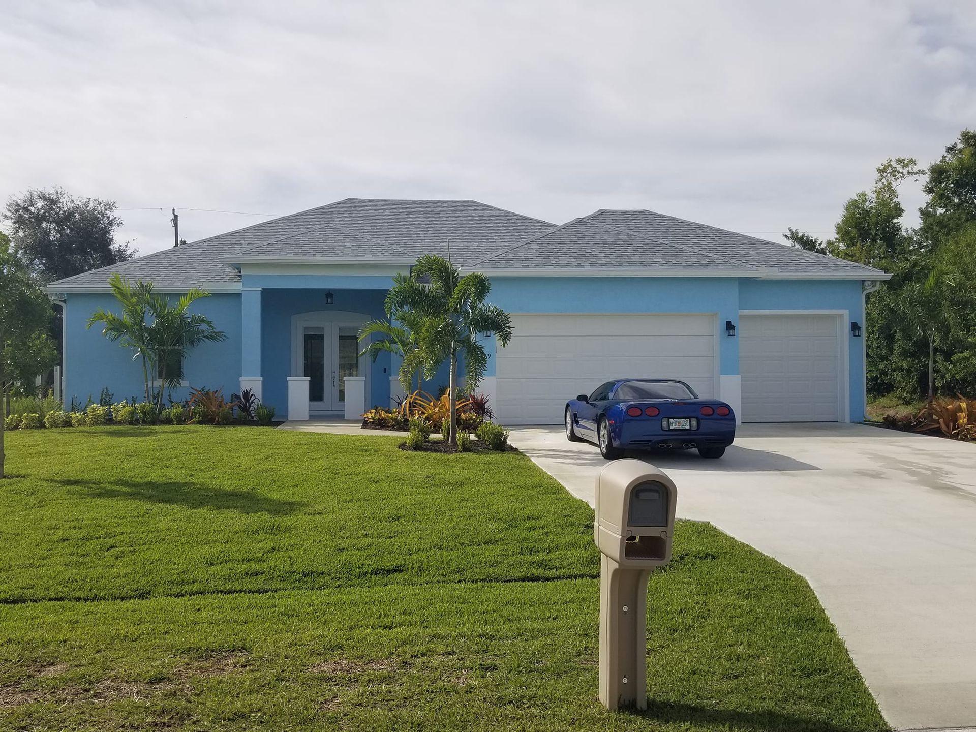 A blue car is parked in front of a blue house