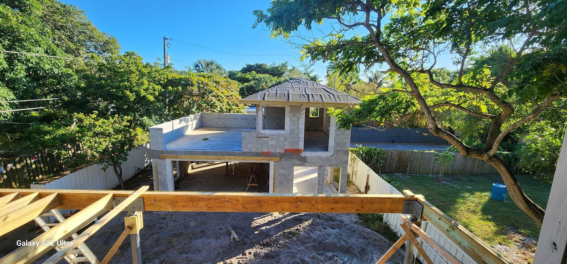 A house that is being built with a lot of trees in the background.