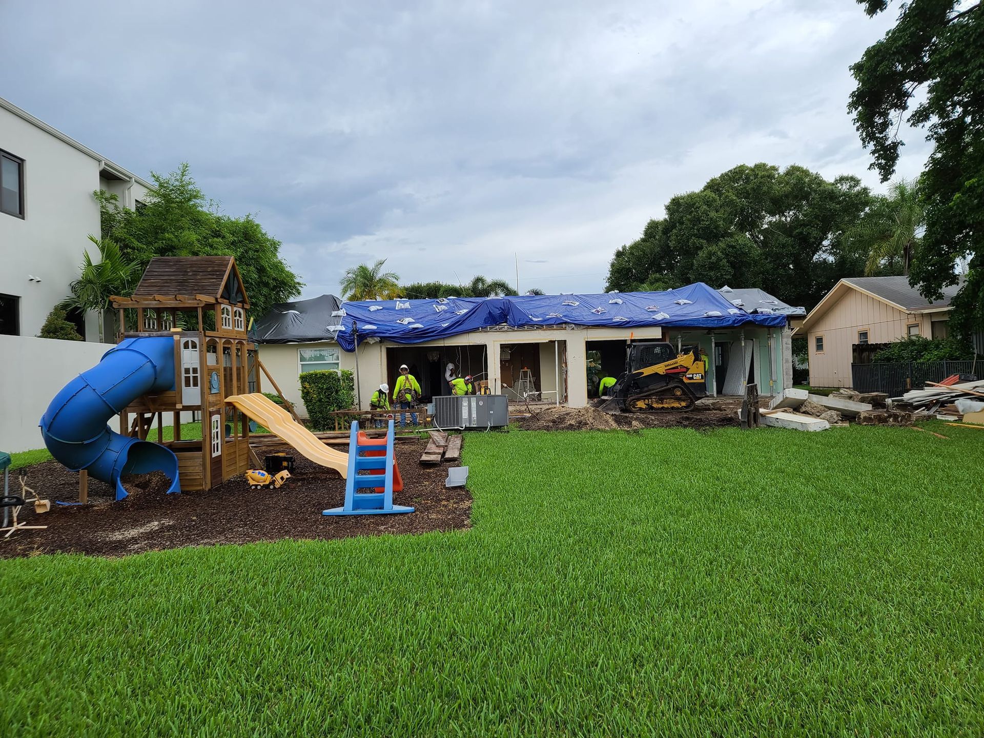 A backyard with a playground and a house under construction.
