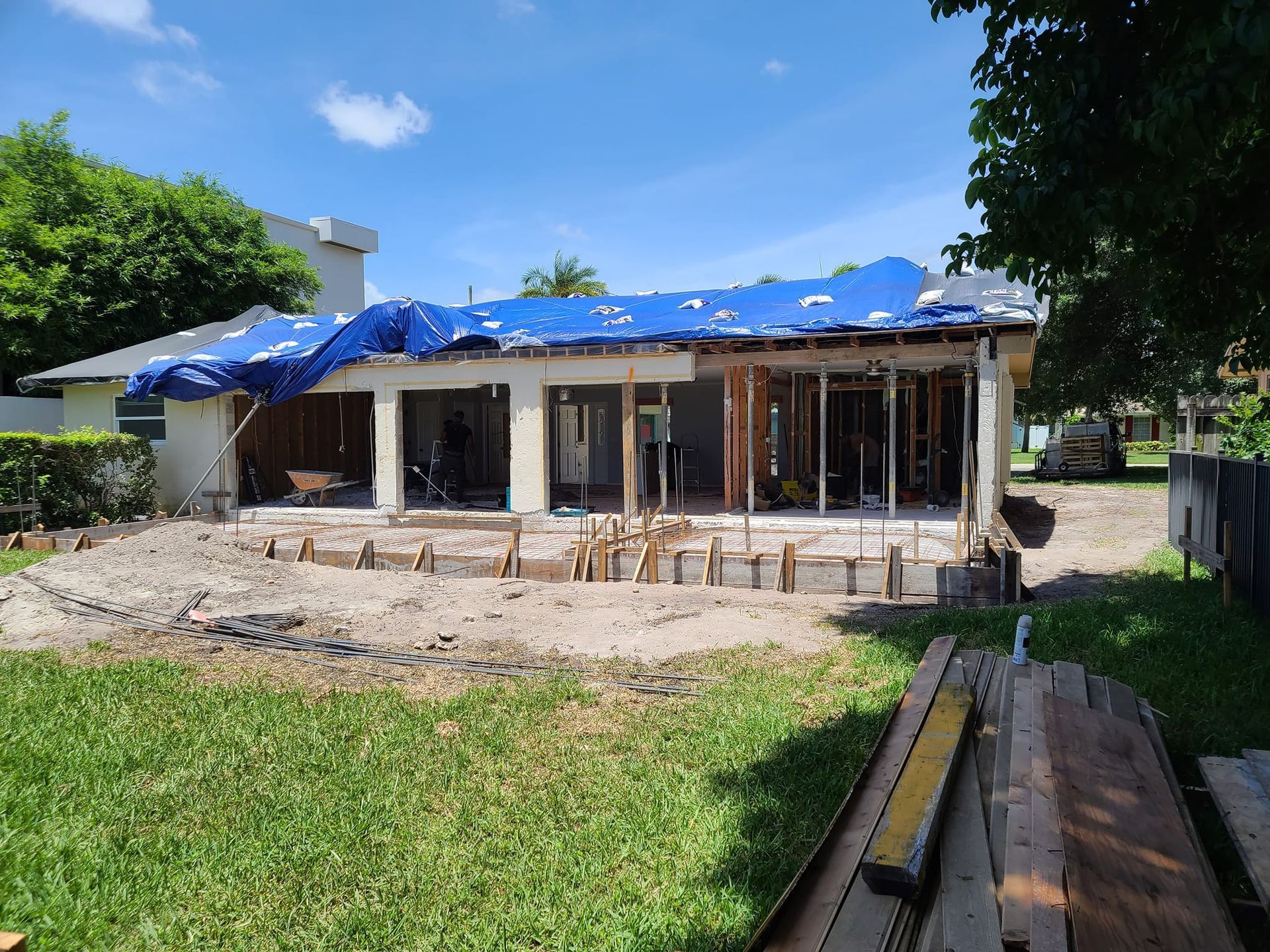 A house under construction with a blue tarp on the roof