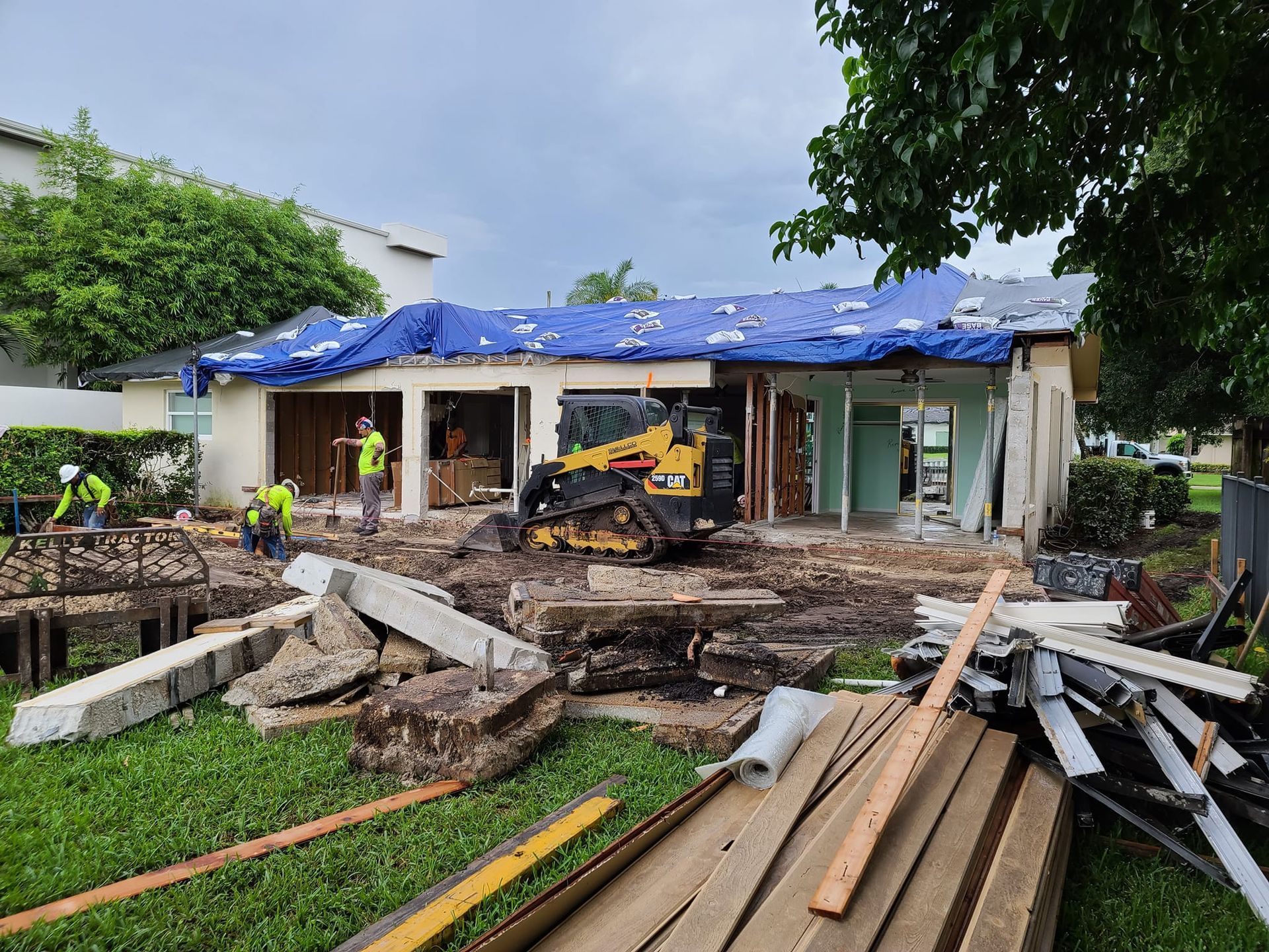A house is being remodeled with a bulldozer in the backyard.