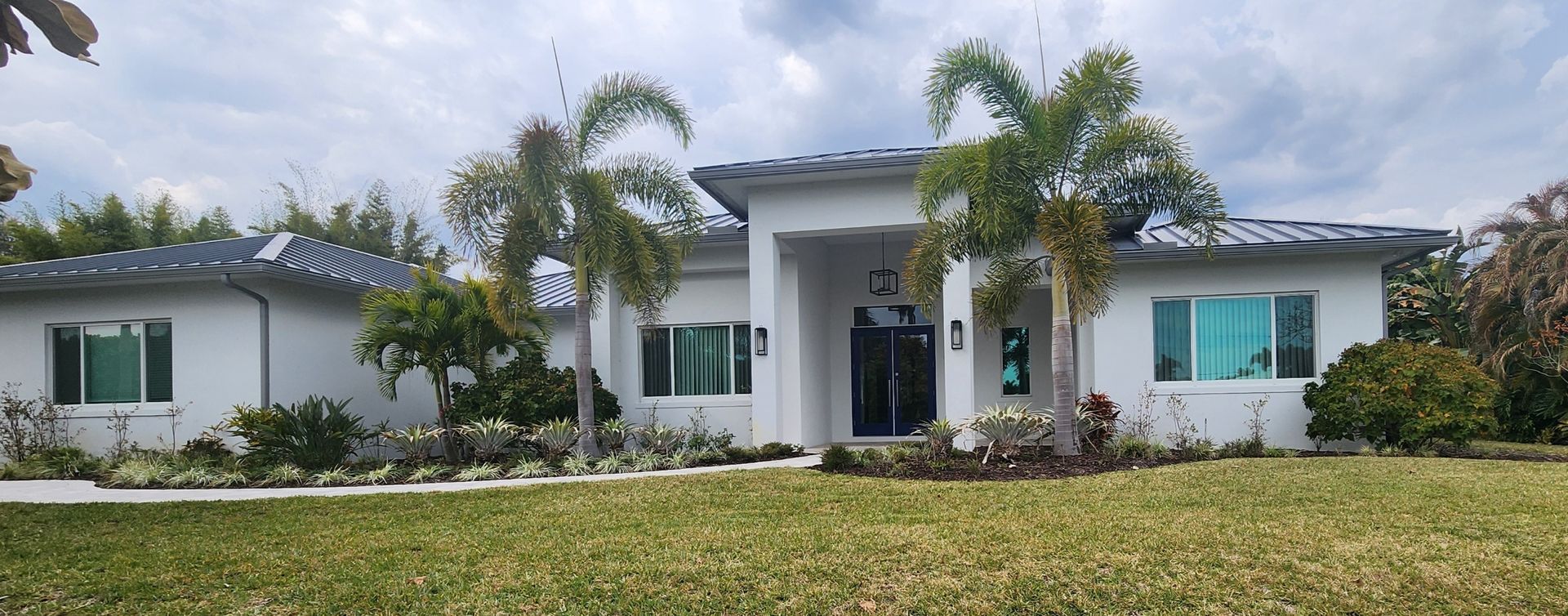 Construction site with scaffolding, workers, and unfinished building under a blue sky.