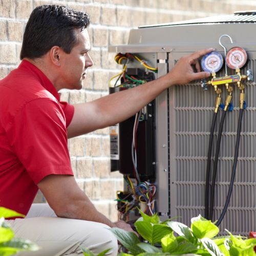 A man in a red shirt is working on an air conditioner
