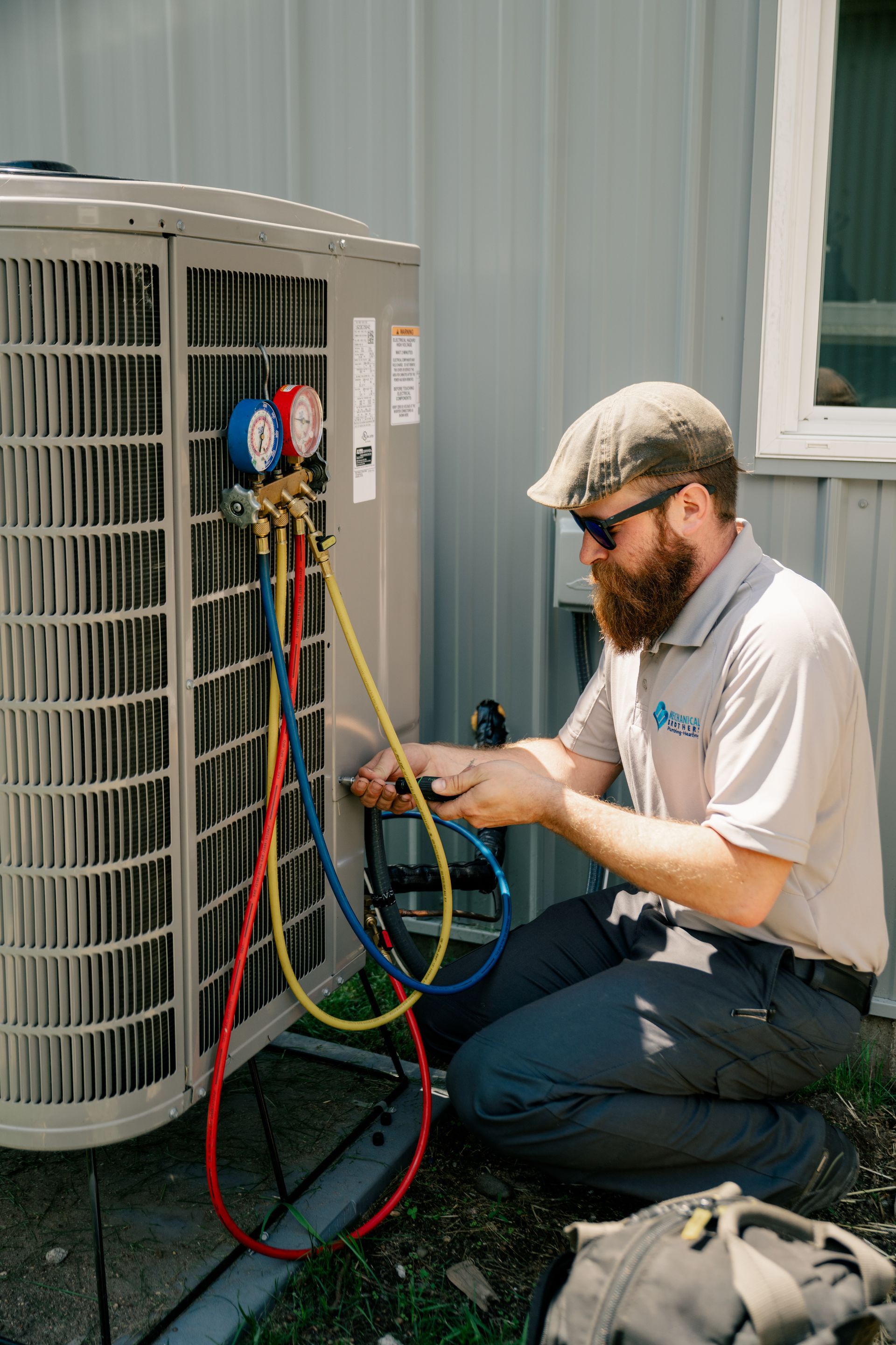 A man is working on an air conditioner outside of a building.