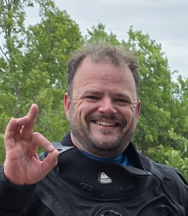 Man in diving suit smiles, gives 