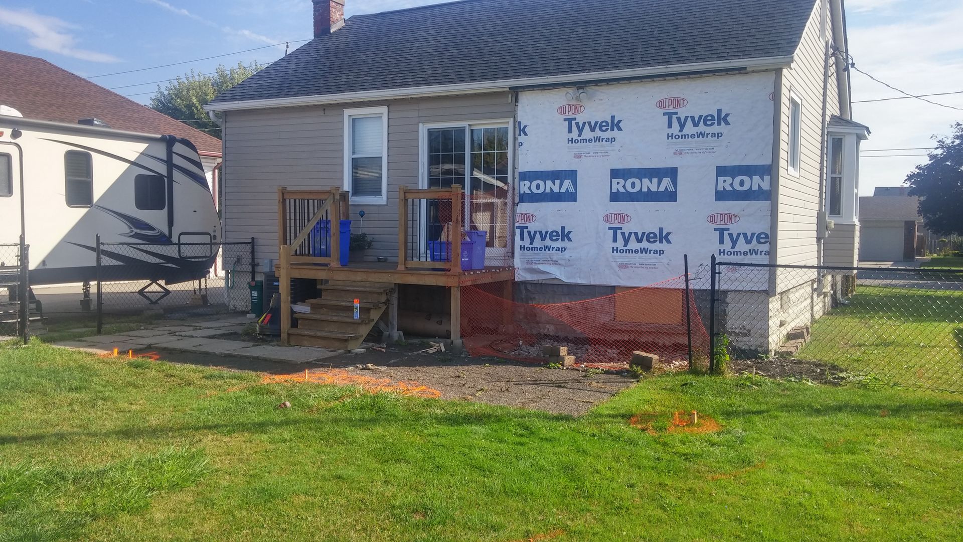 A house is being remodeled with tyvek siding and a deck.