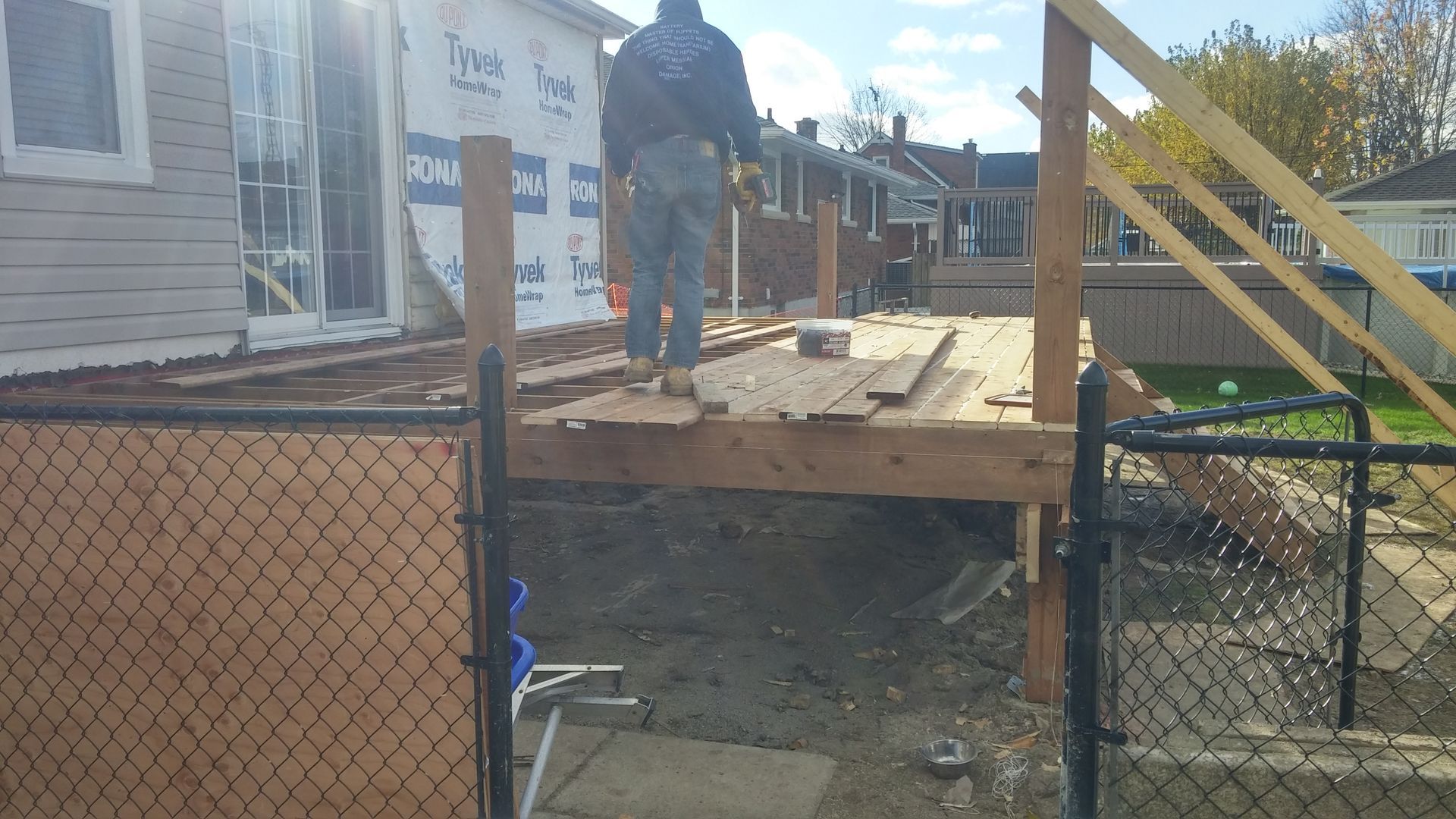 A man is standing on a wooden deck in front of a house.