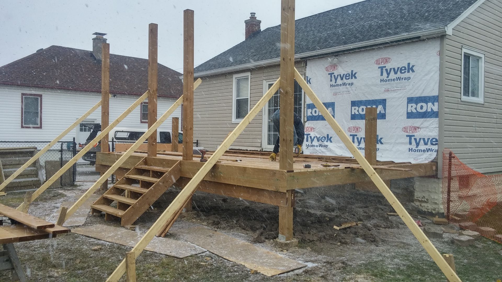 A wooden deck is being built in front of a house.