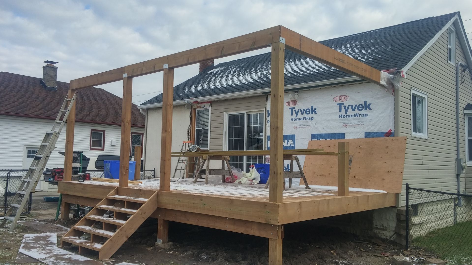 A wooden deck is being built in front of a house.