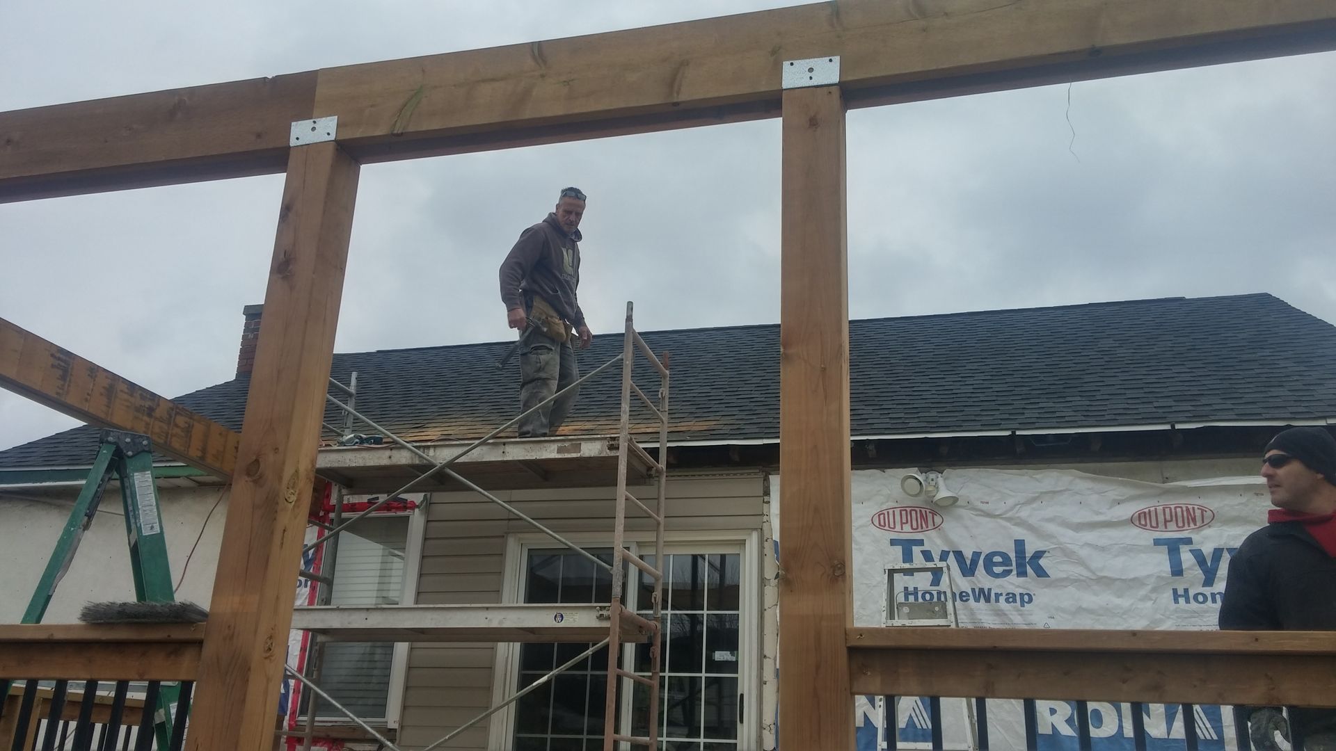 A man is standing on a scaffolding on the roof of a house.
