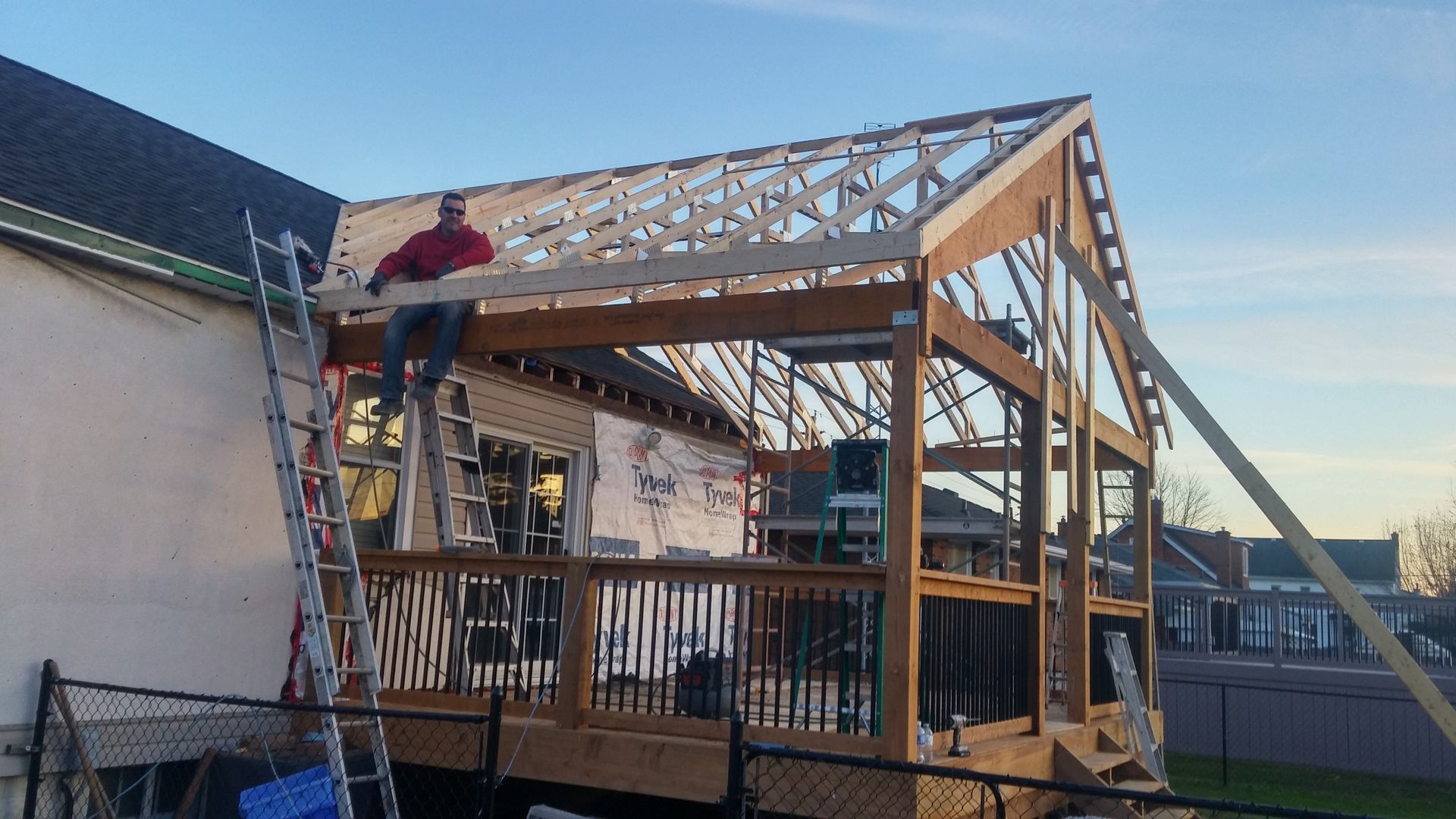 A man is standing on a ladder on top of a wooden structure.