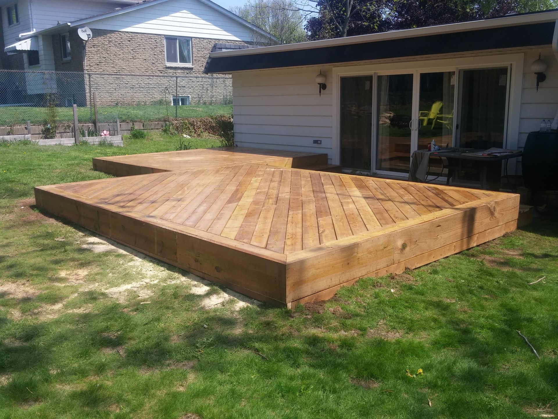 A wooden deck is sitting in the grass in front of a house.