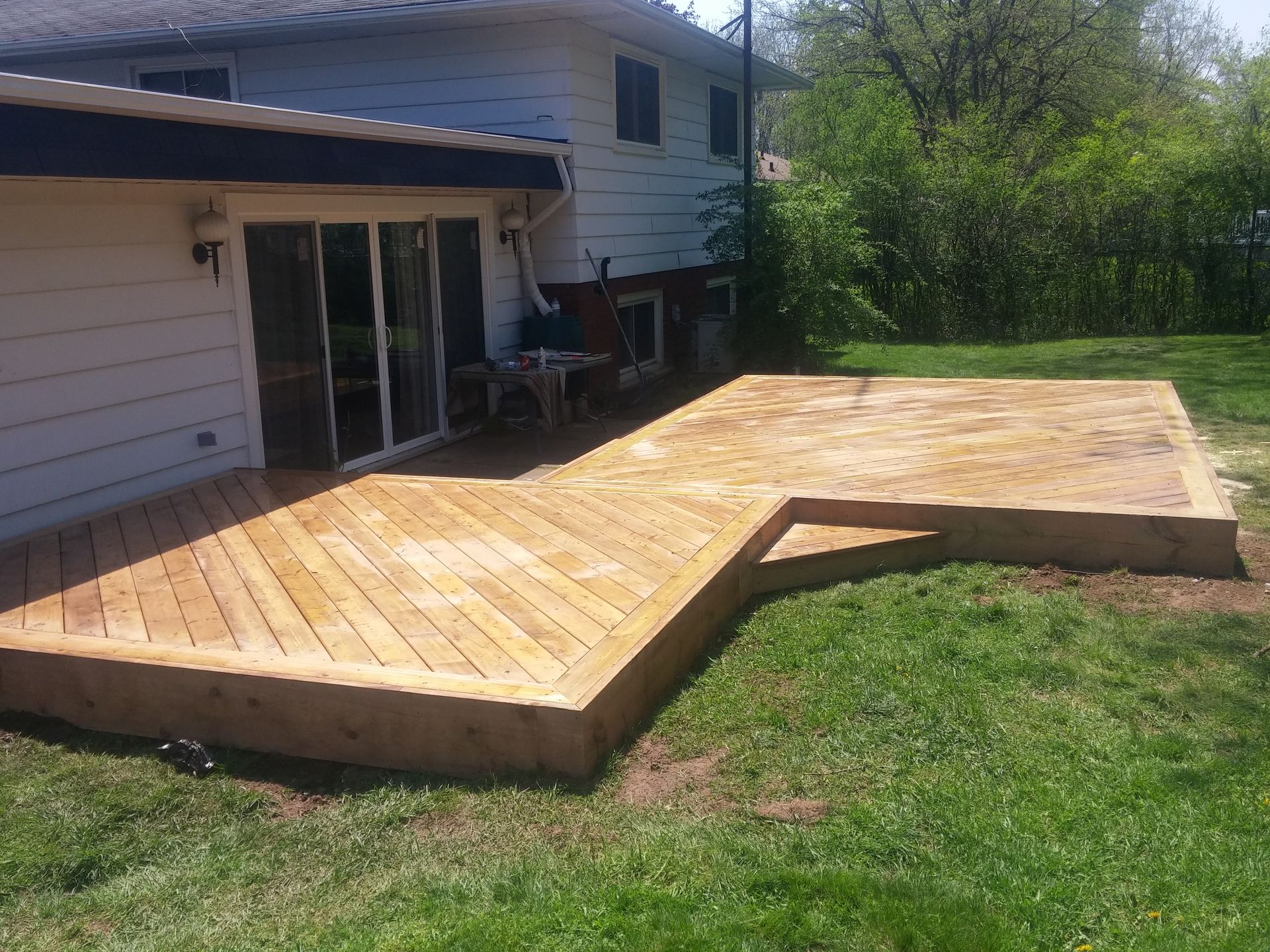 A large wooden deck is in the backyard of a house.
