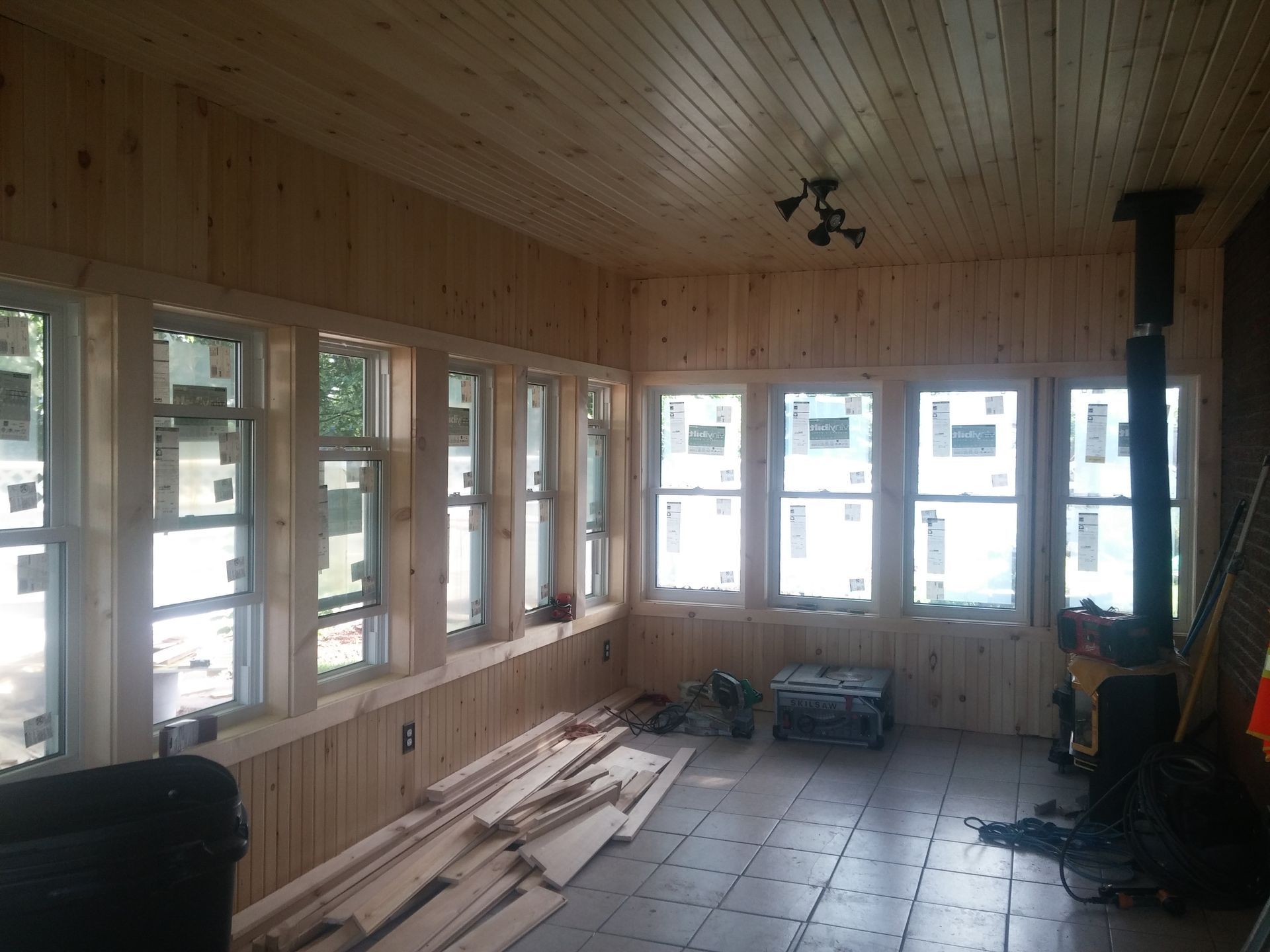 A room with a lot of windows and a wood stove.