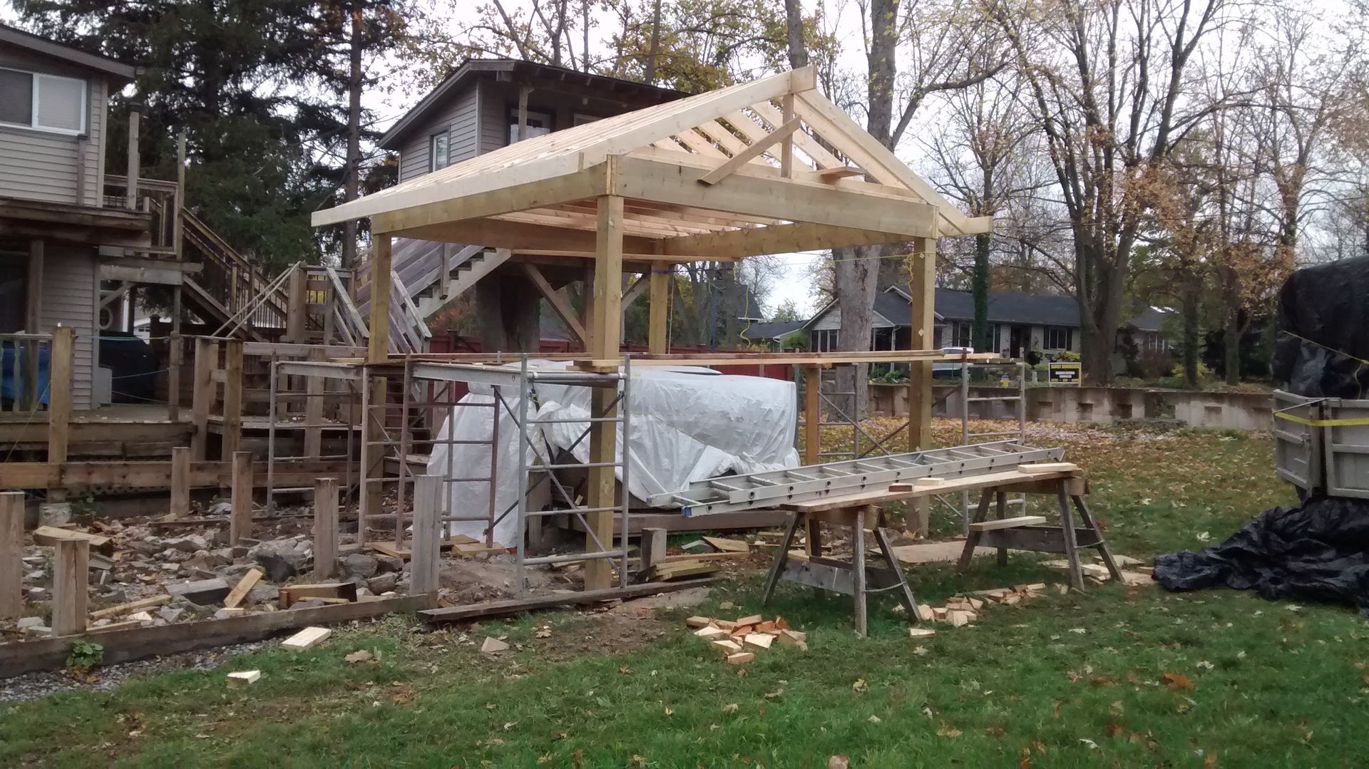 A wooden structure is being built in the backyard of a house.