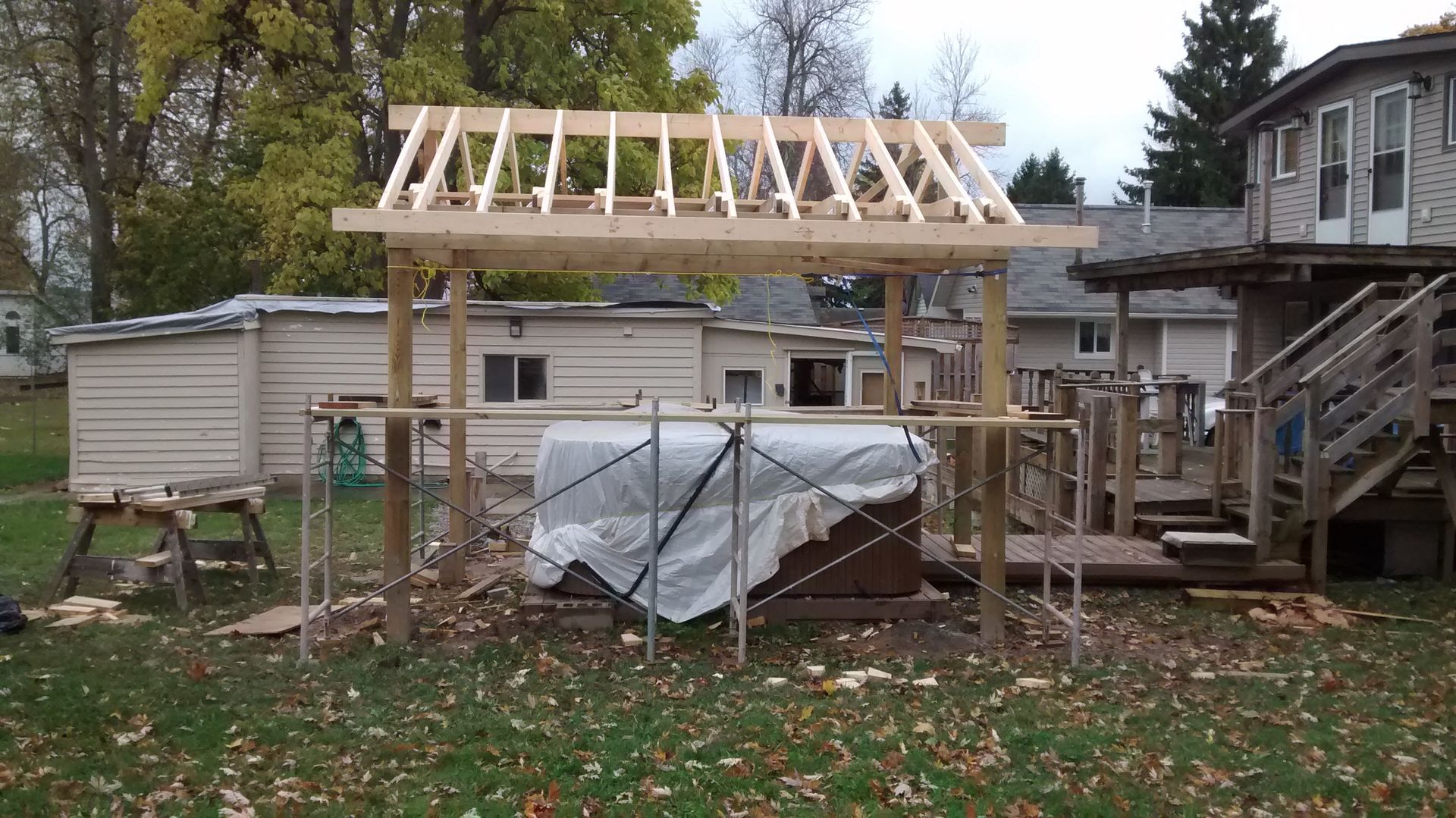 A wooden structure is being built in the backyard of a house.