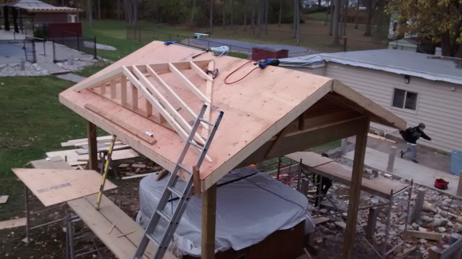 A roof is being built over a hot tub in a backyard.